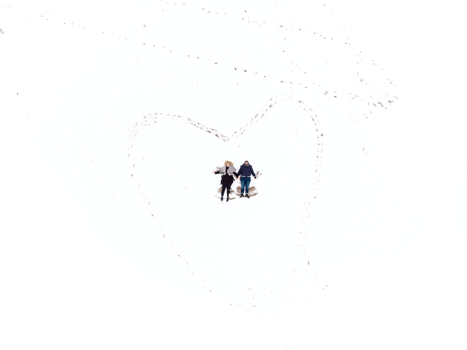 a couple of people standing next to each other on top of a snow covered ground