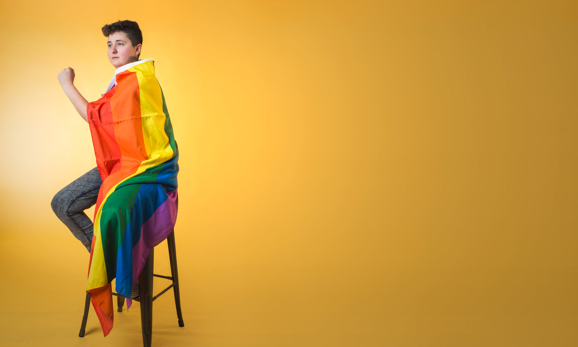 a man with rainbow stripes is sitting on a stool