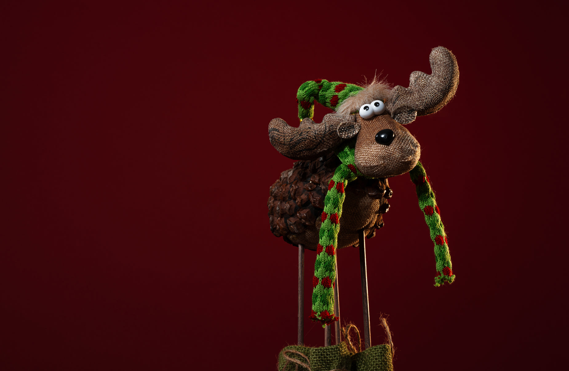a stuffed moose made from cotton has a scarf and hat on top
