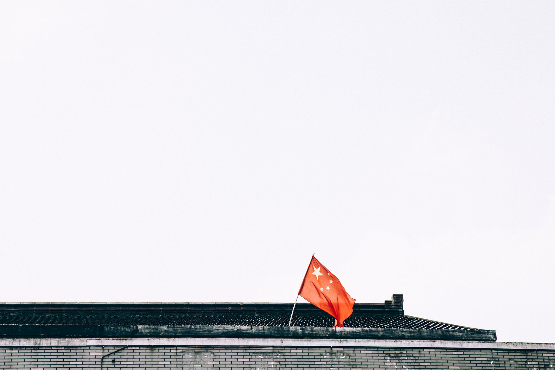 there is a red and black flag that is on top of a building