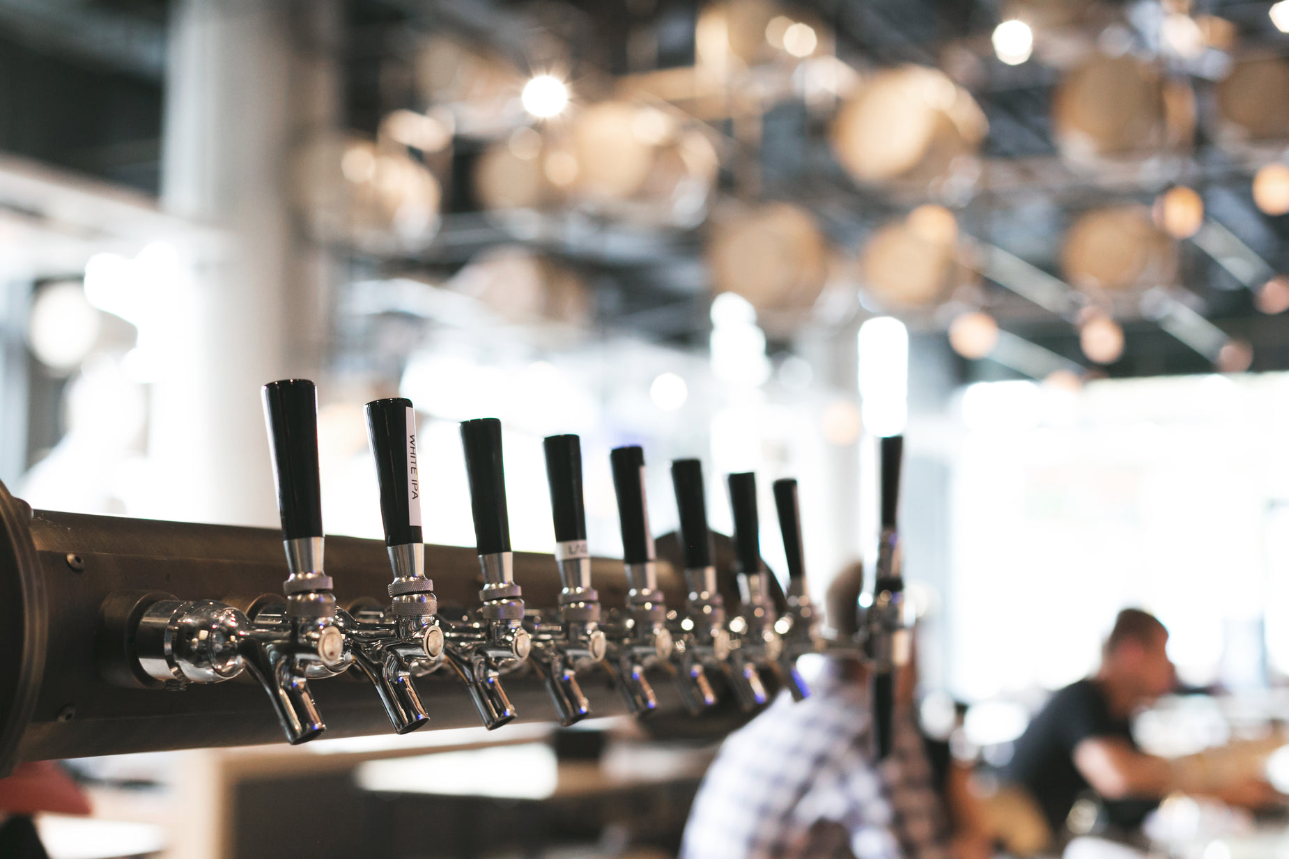 a row of beer taps in a bar with several men