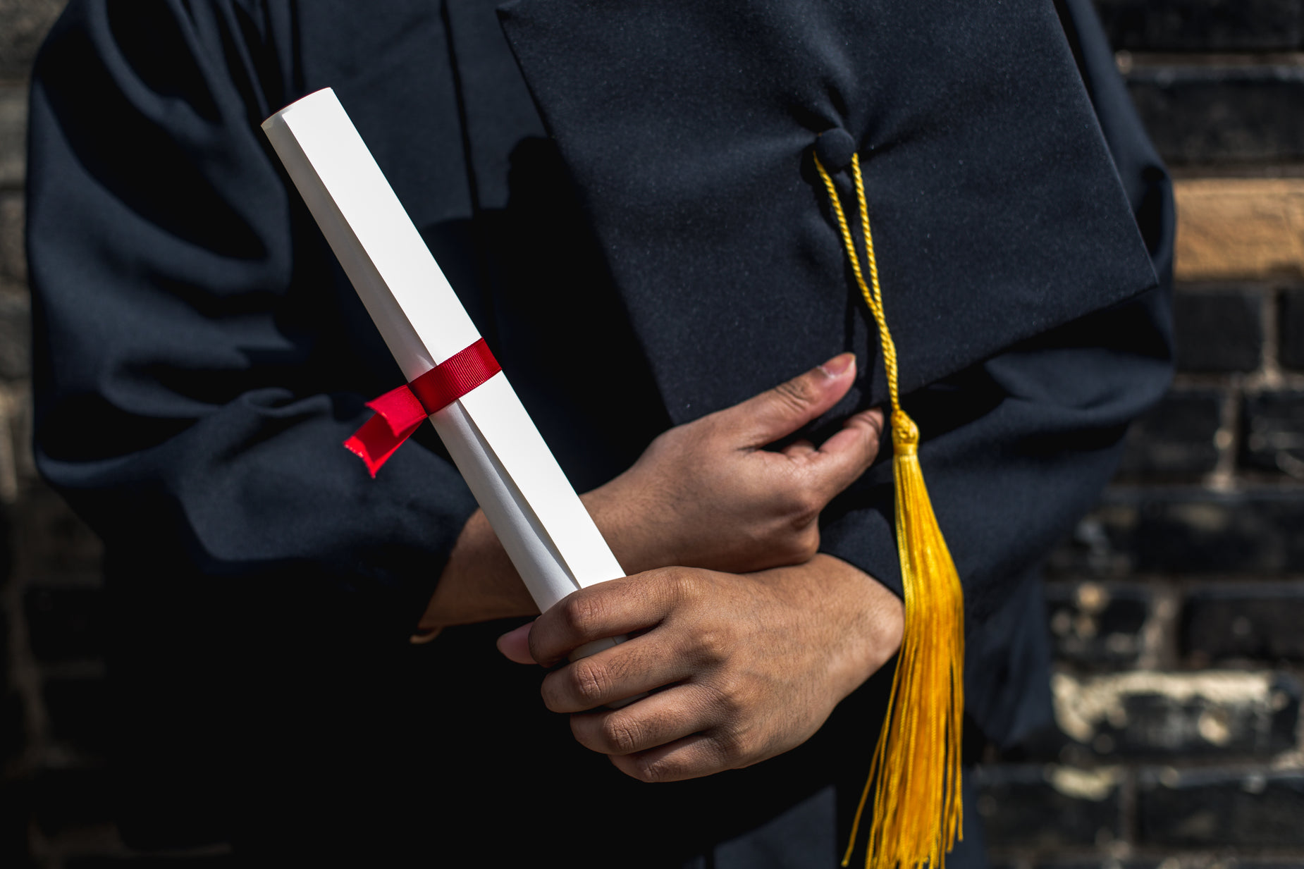 a person wearing a black graduation gown holding a red and white diploma