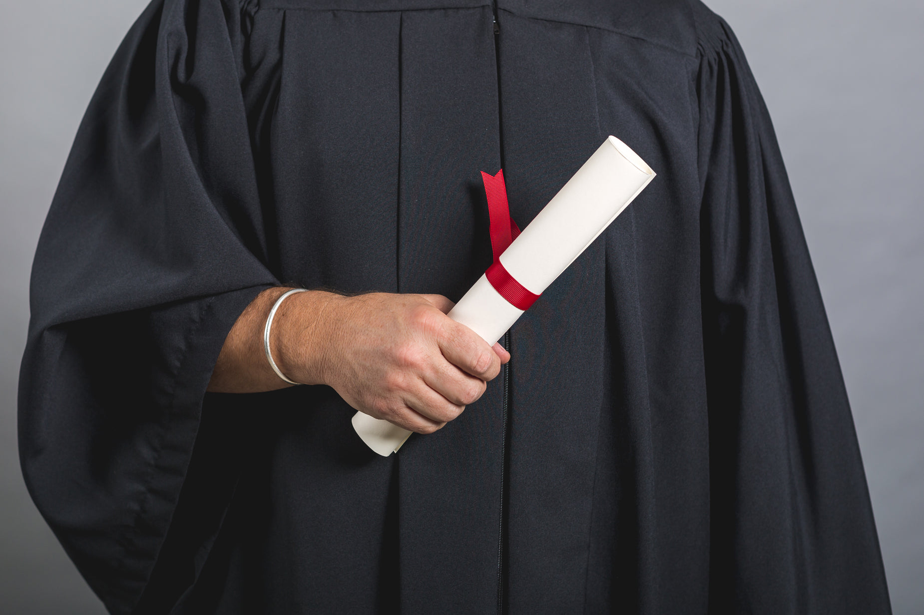 a graduate wearing a graduation gown and red graduation ribbon