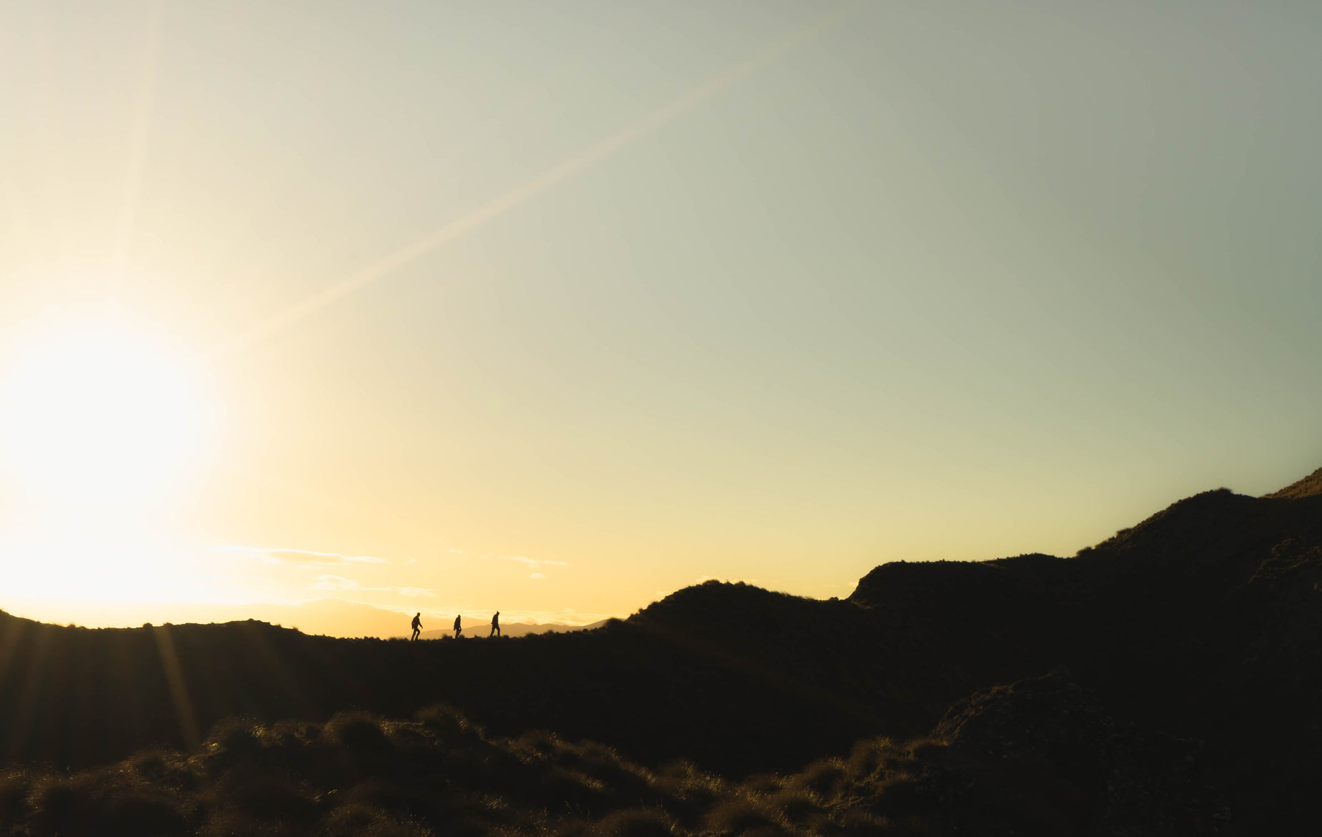 a pair of people are standing on a hill as the sun sets