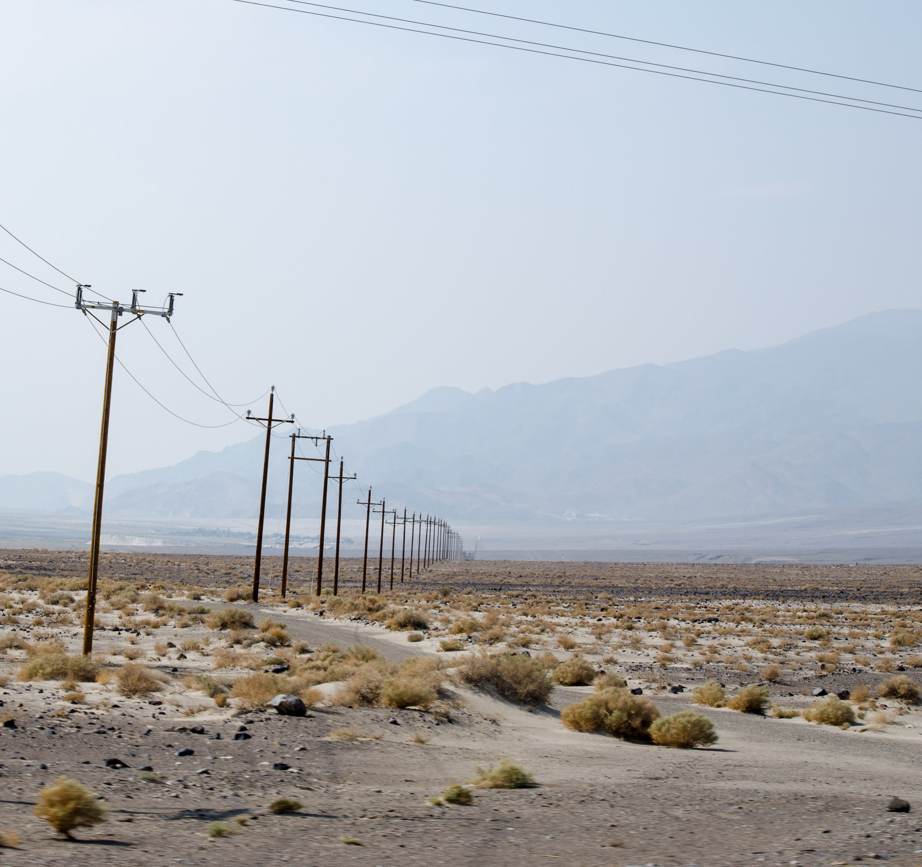 a group of power poles with mountain view in background