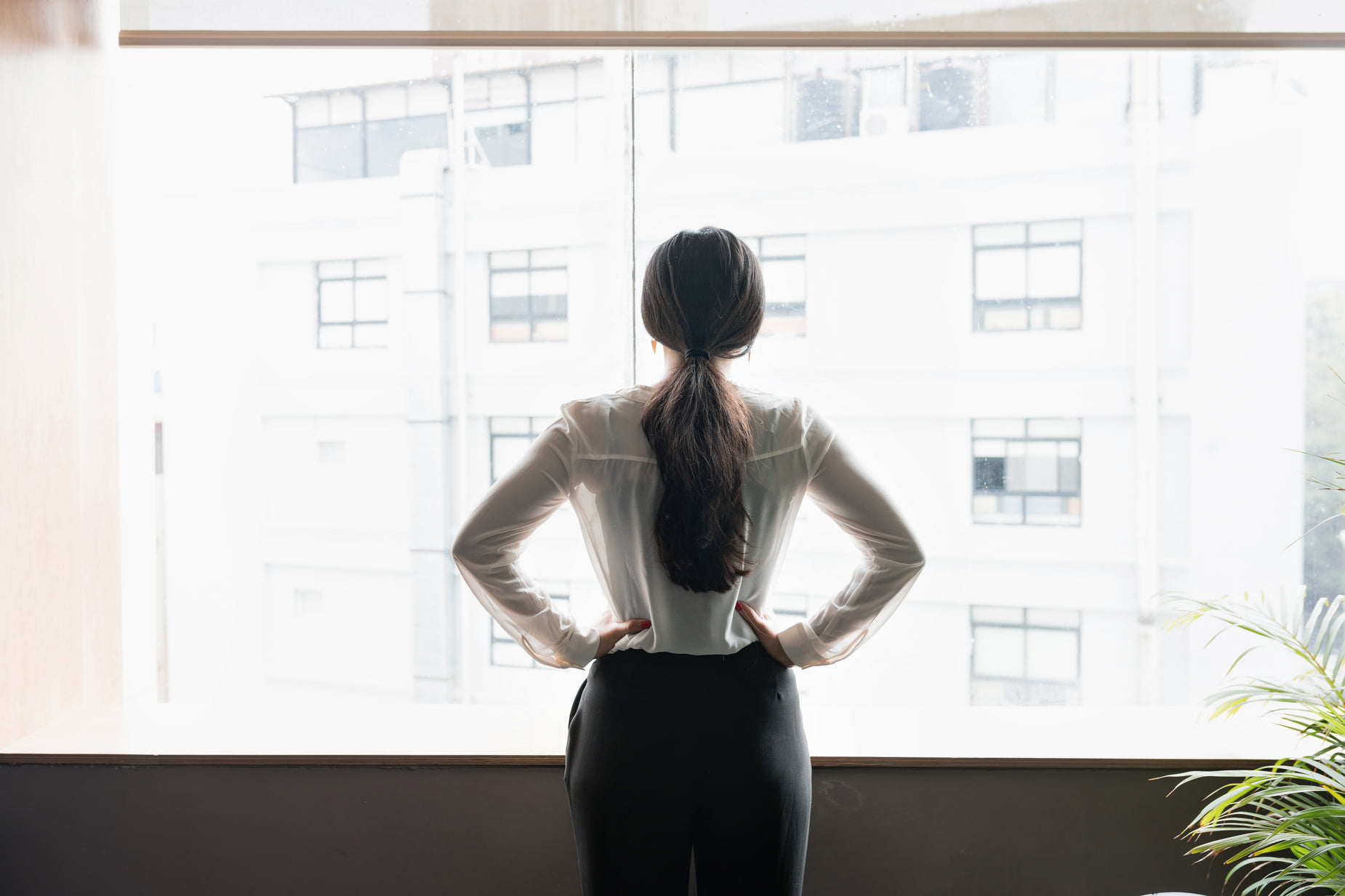 a woman standing up against a window looking out at the city