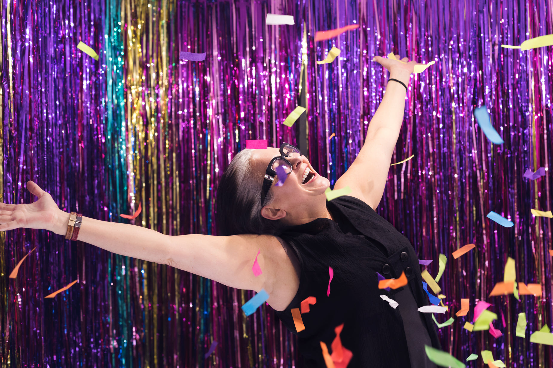 woman in black dress posing for picture in front of purple wall