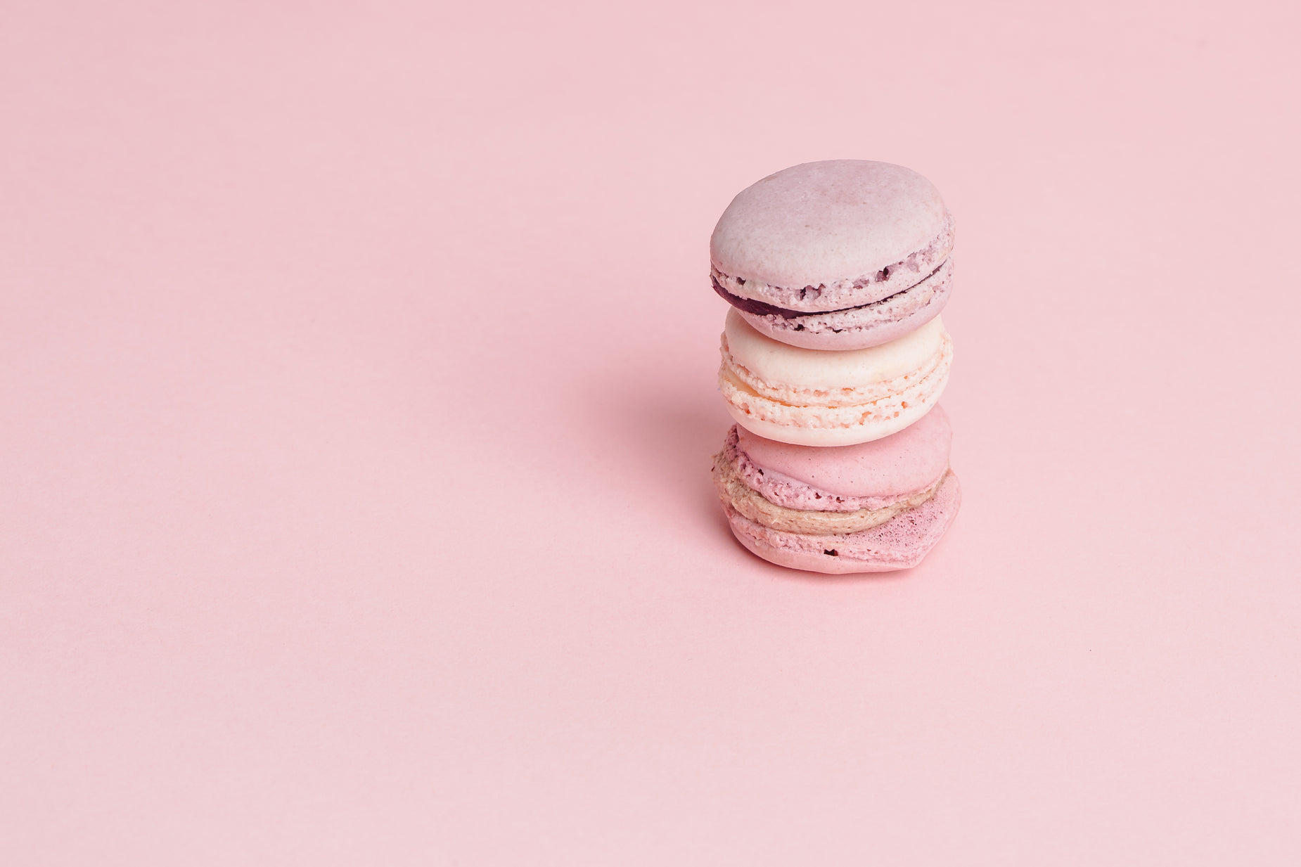 three macaroons sitting on a pink surface
