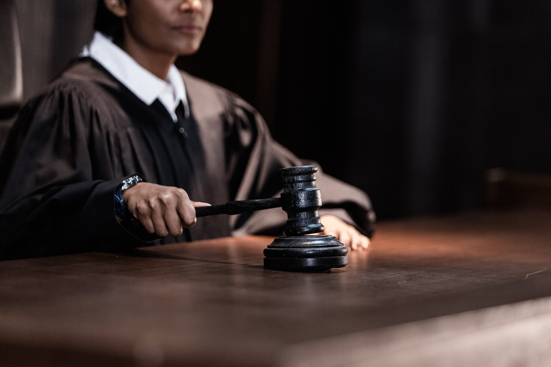 a person in law robes holds the gaven above their head