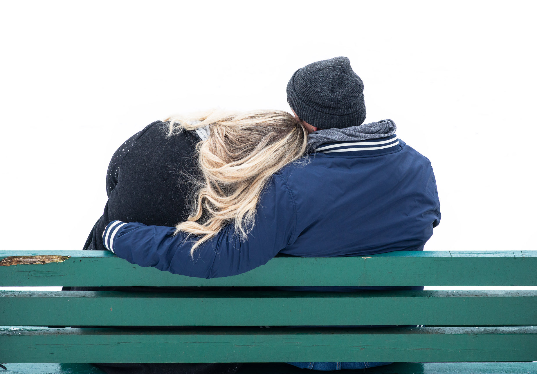 two people sitting on a bench side by side