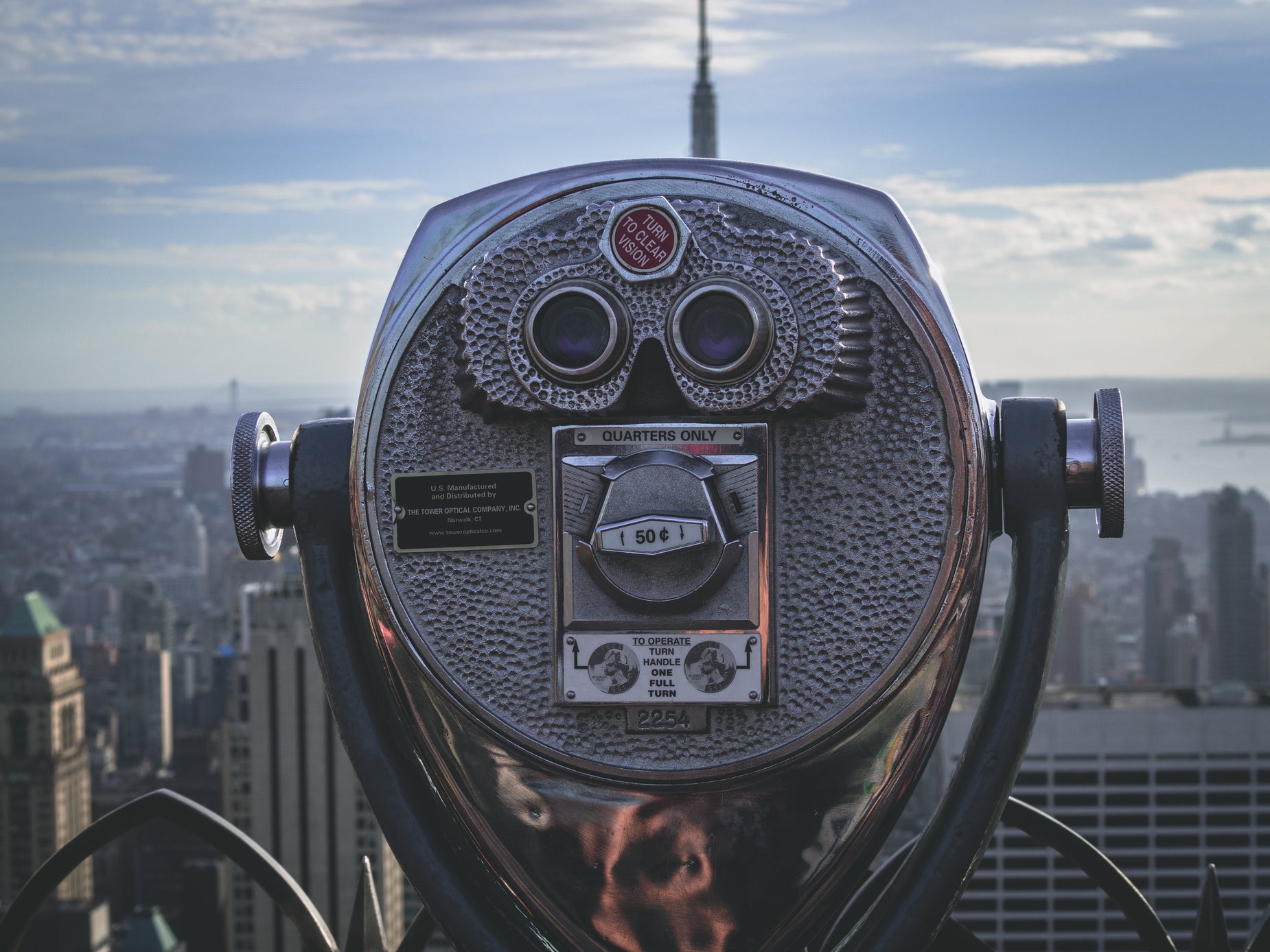 a silver metal coin meter with a city in the background