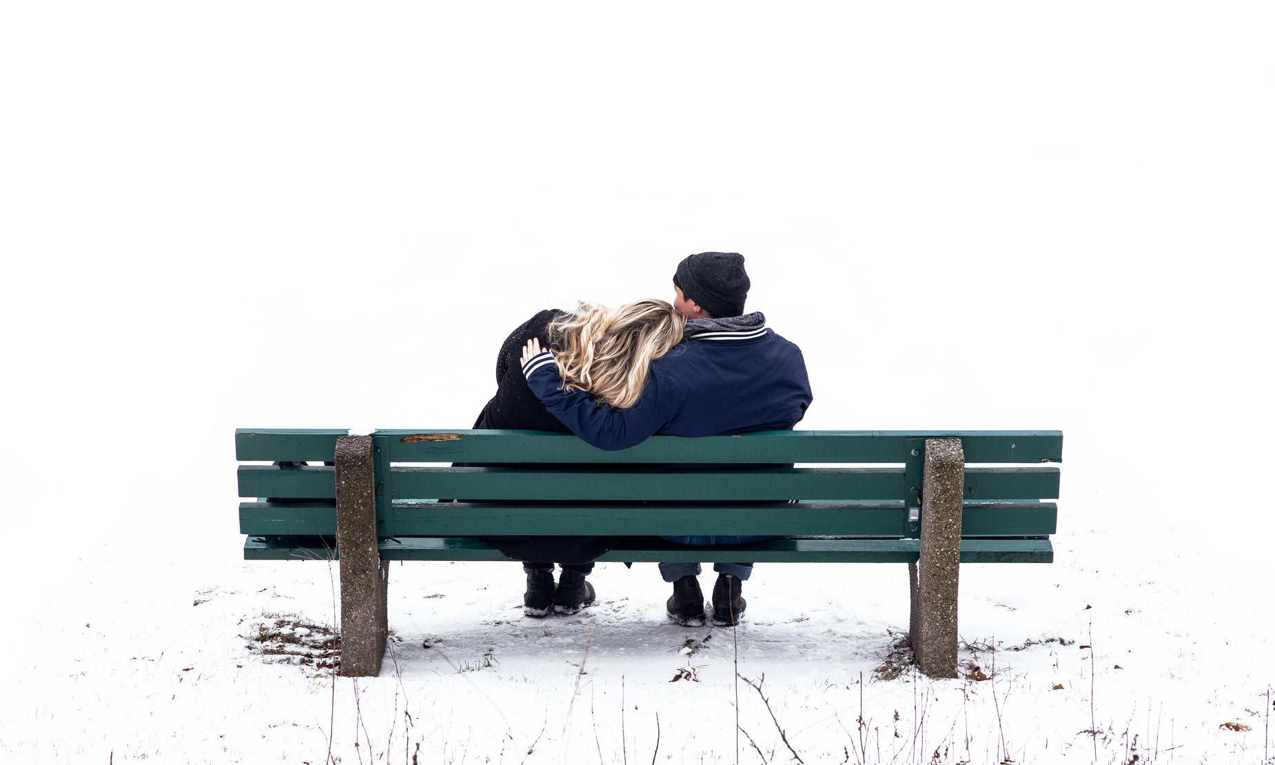 a man and woman sitting on a bench in winter