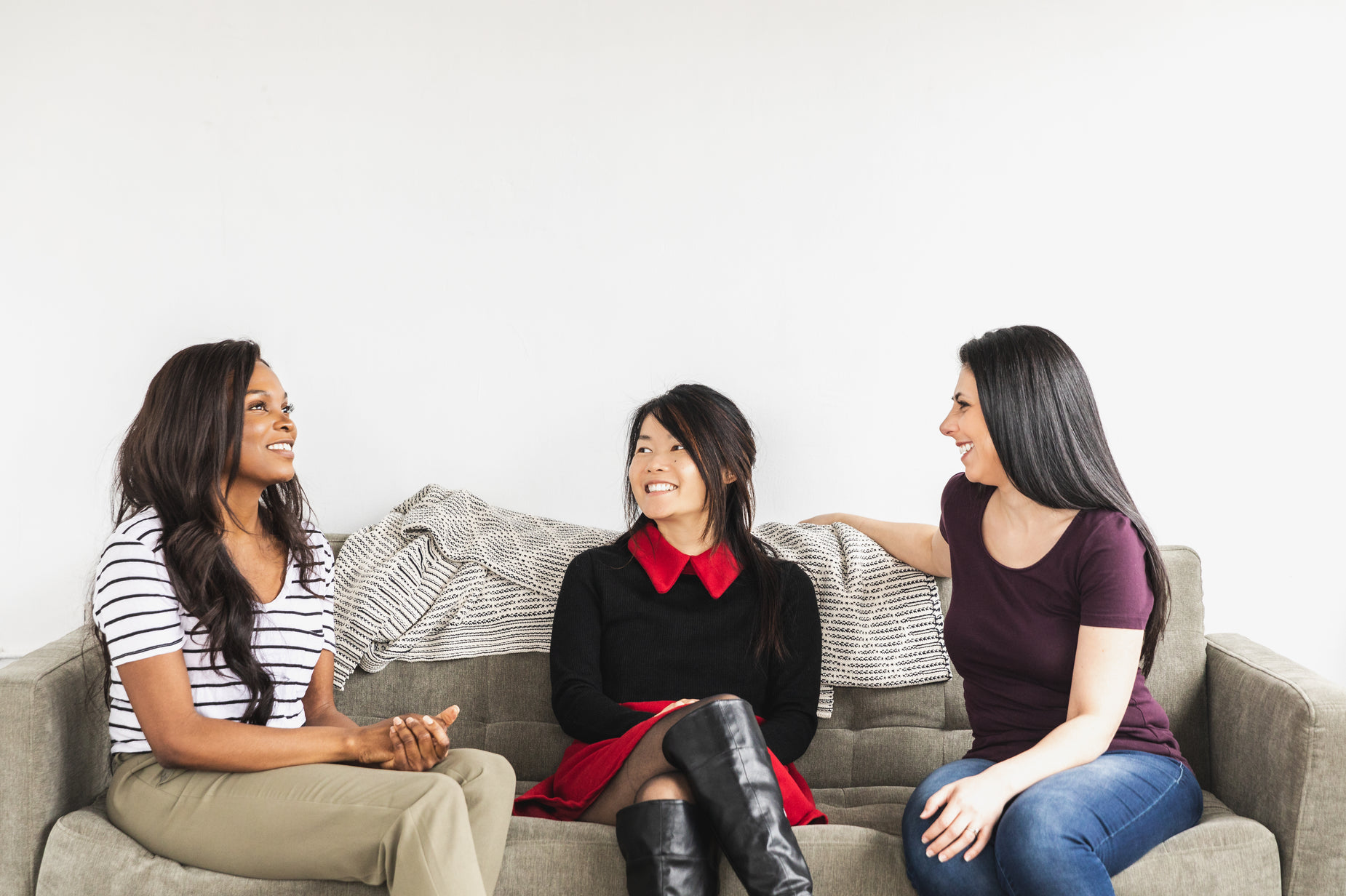 three women talking on a couch in a room