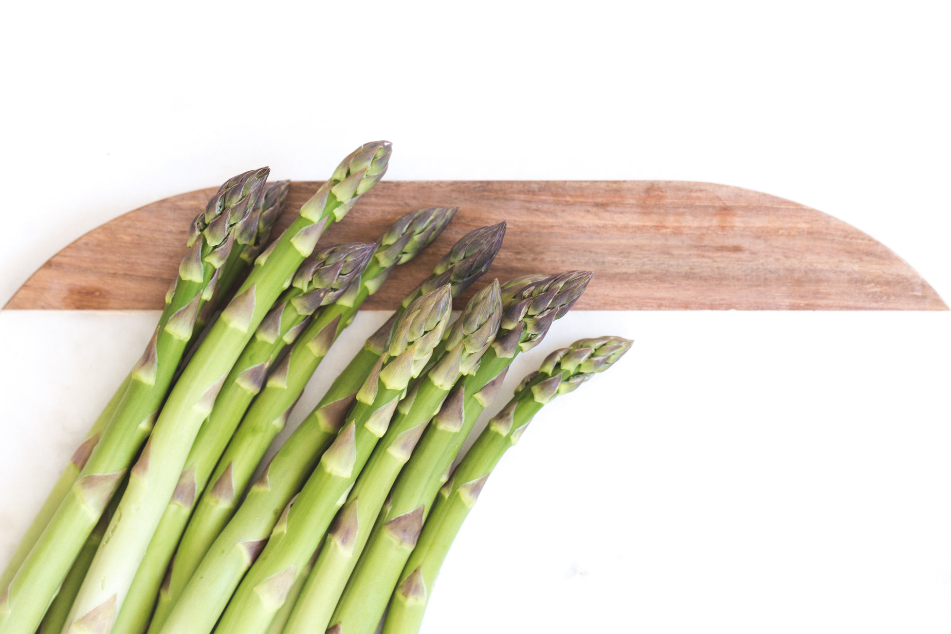 asparagus stems and a  board against a white background
