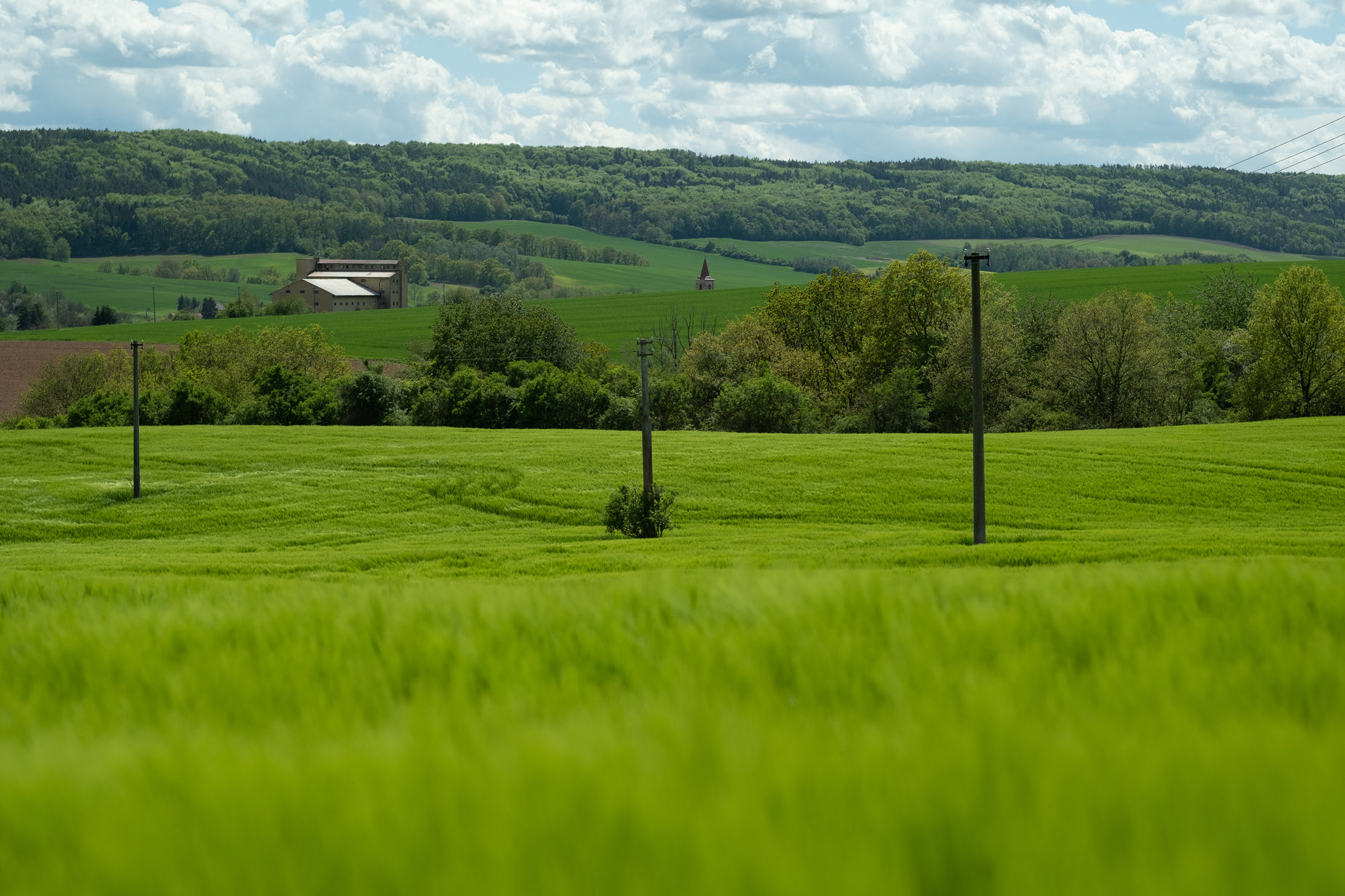 a green field has a farm house in the distance