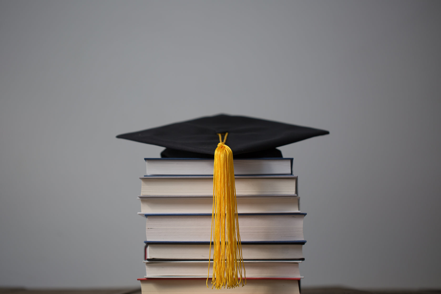a stack of books with a graduation cap and tassel sitting on top