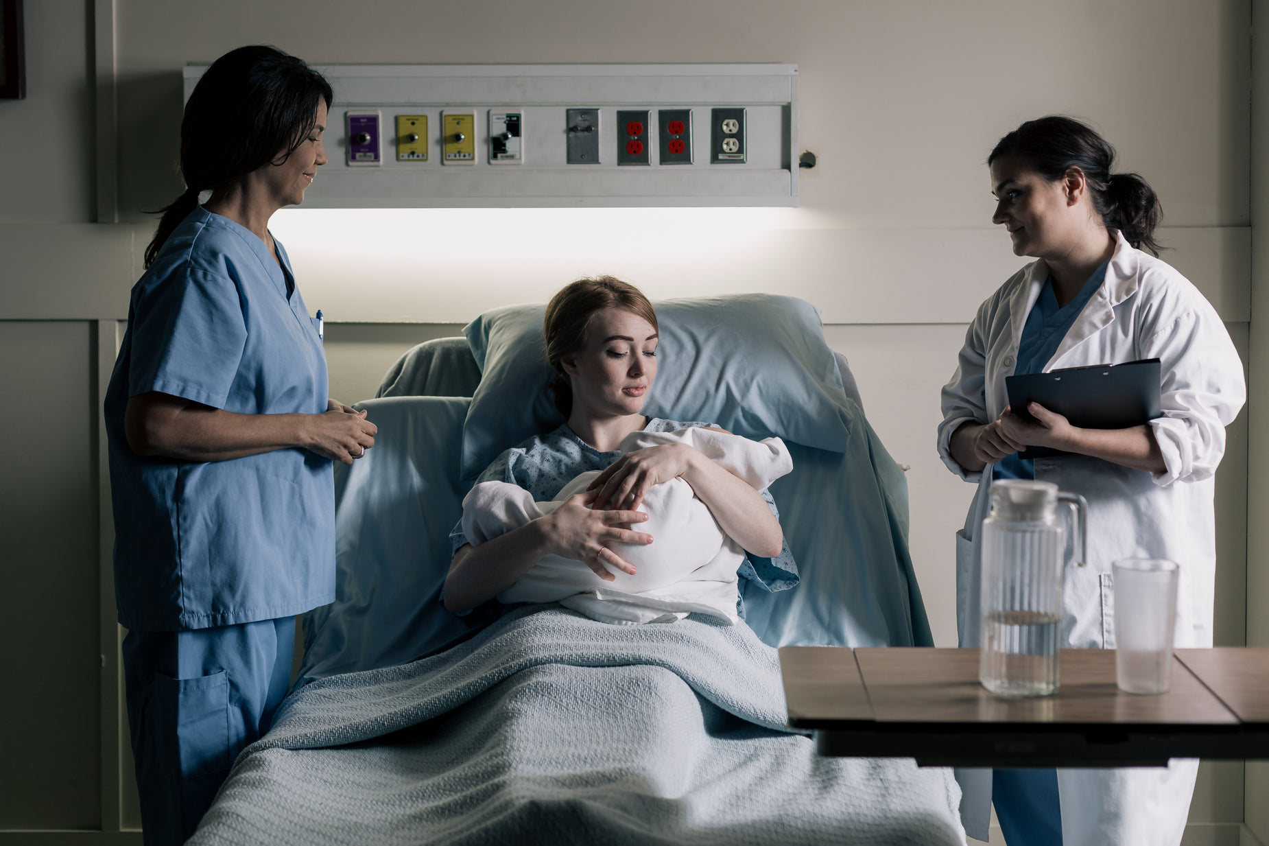 a hospital bed scene with two women and one woman with ivs