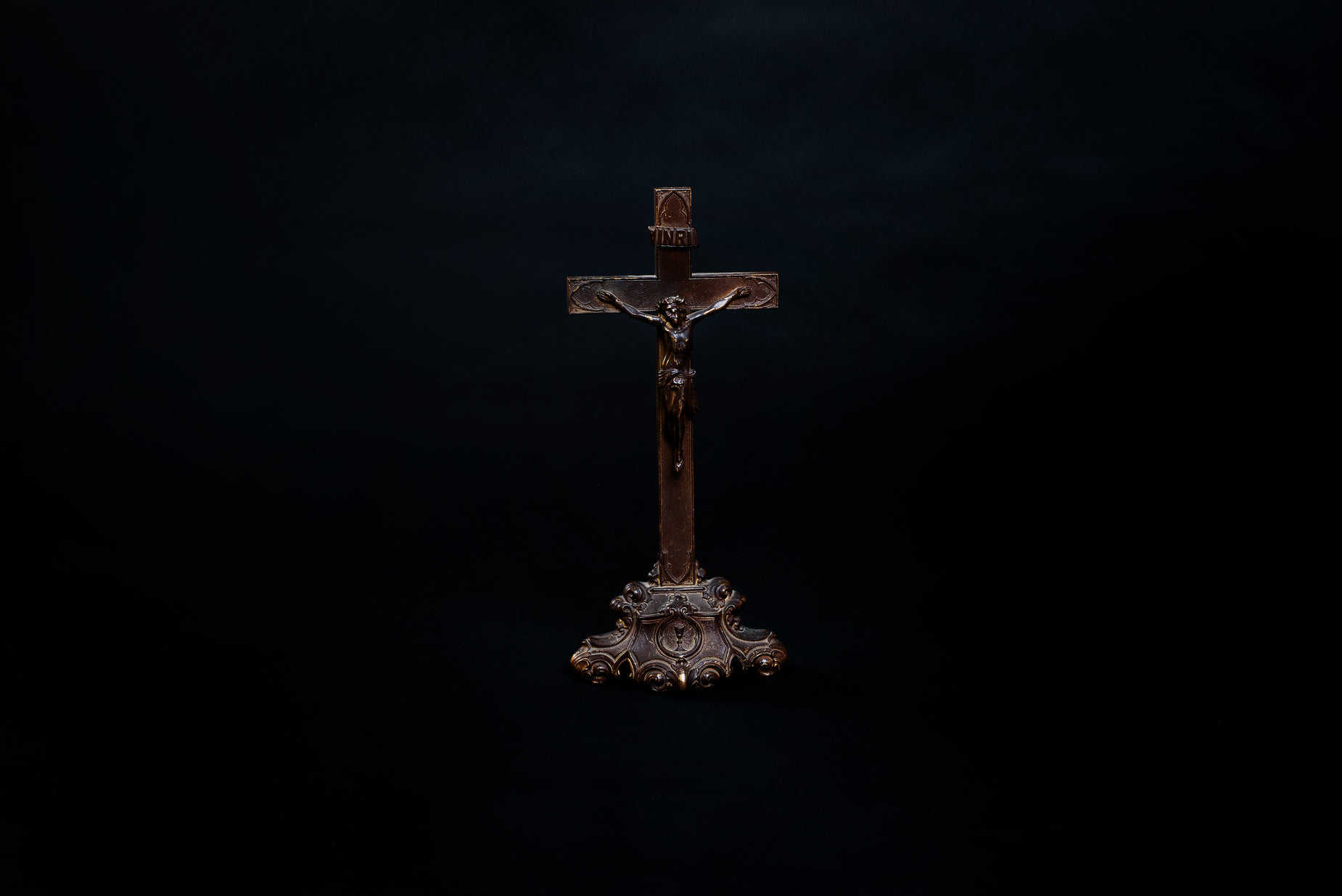 a wooden cross and a black background with only a light on