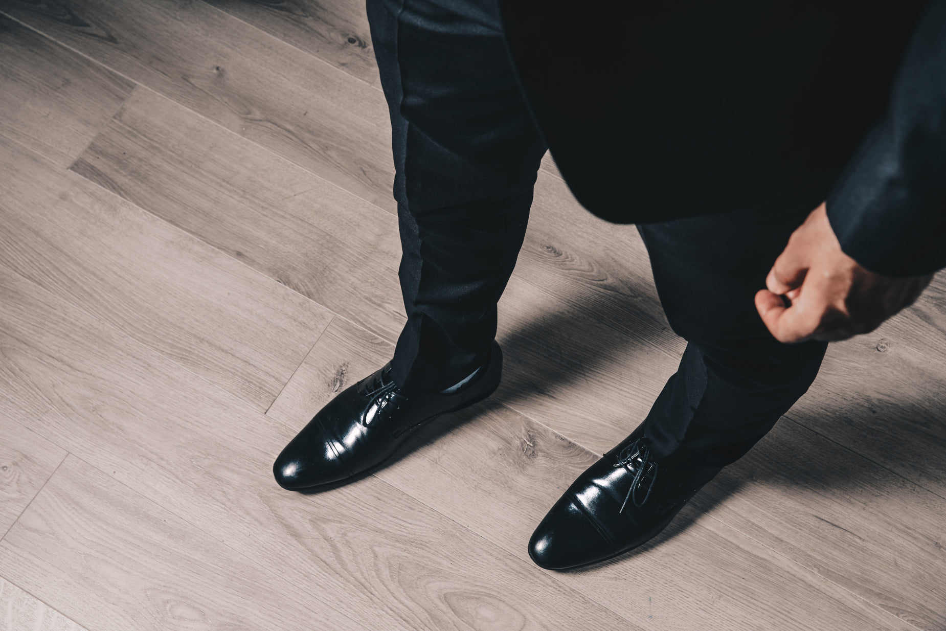 a man wearing a suit is tying up his black shoes