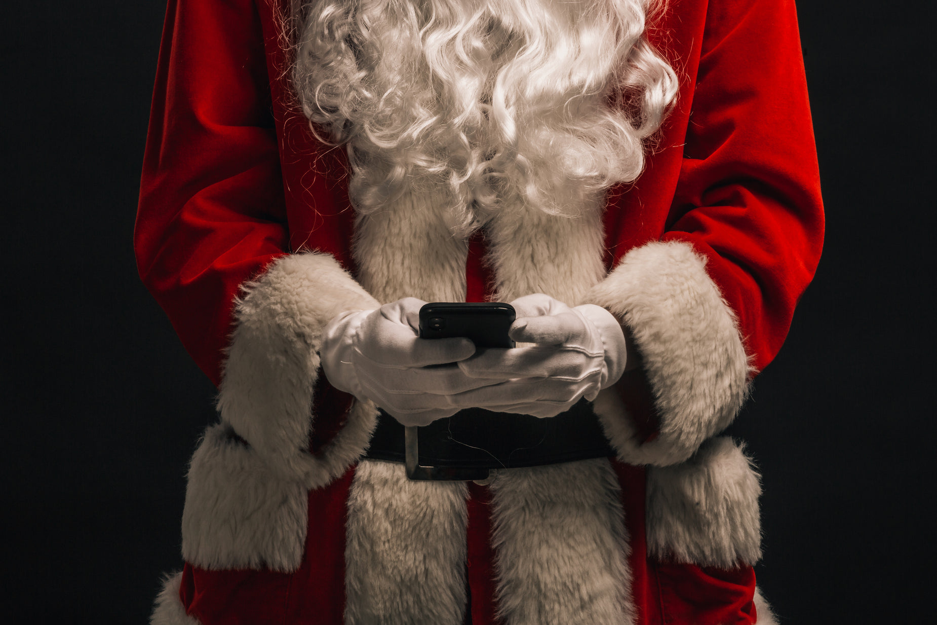 a man dressed up in a santa suit and holding his phone