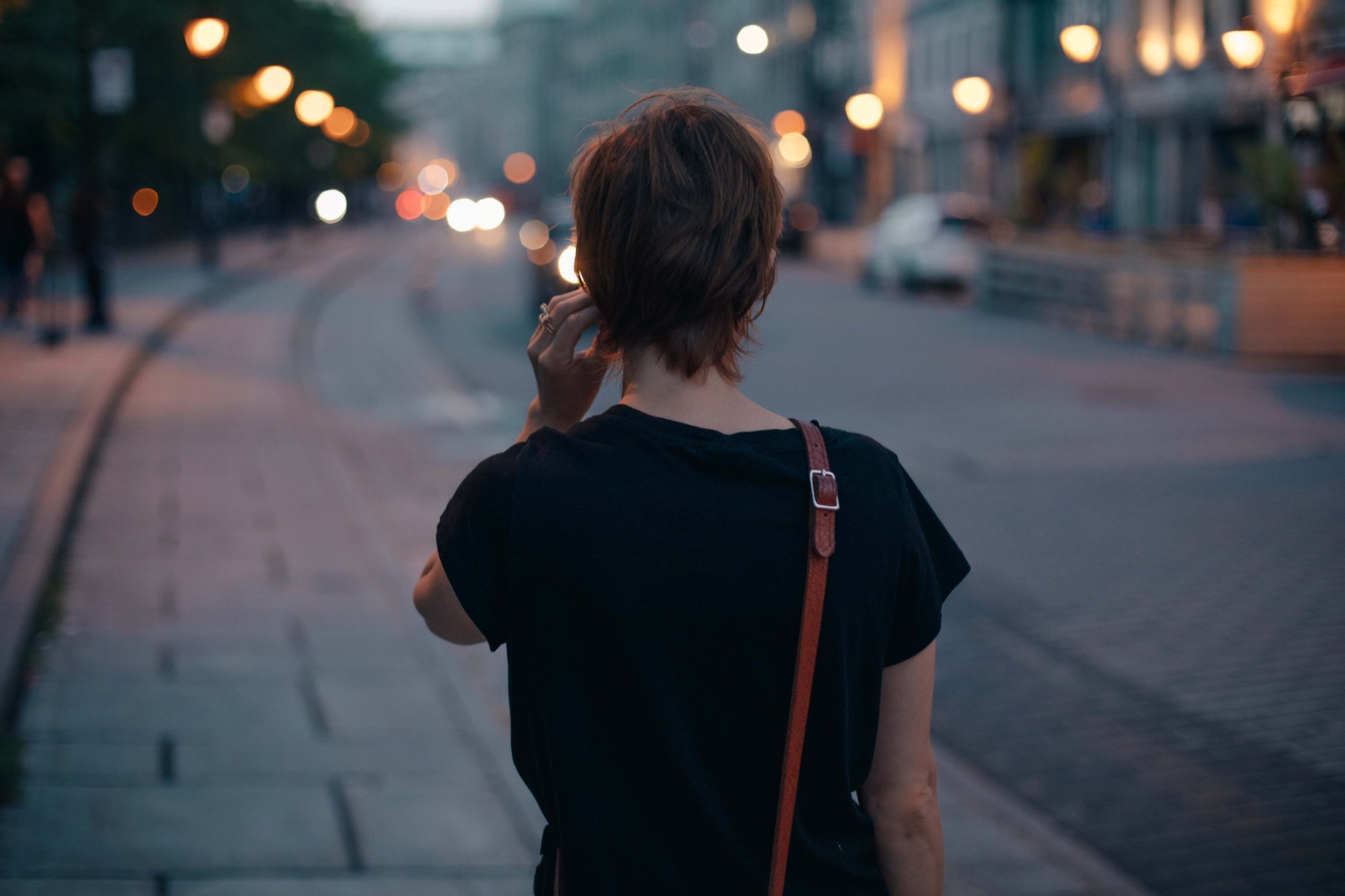 a woman walks down the sidewalk and talks on her phone