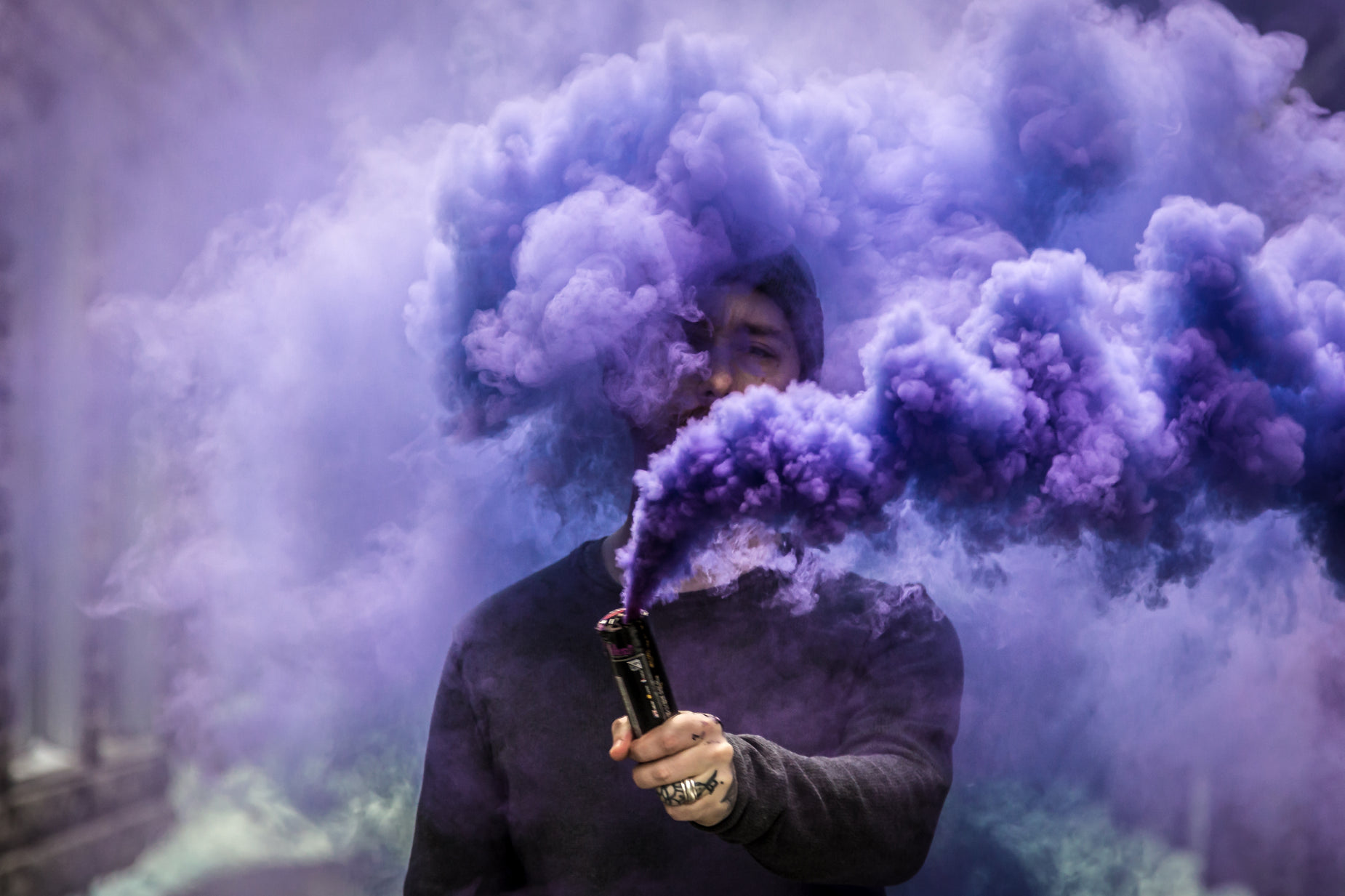 a man smoking an electric cigarette is covered in purple smoke