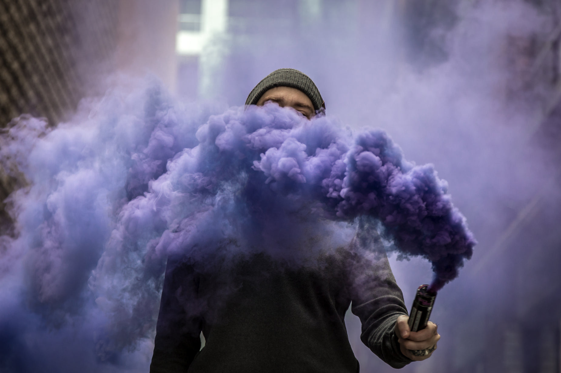 person with purple smoke and cap on holding cellphone