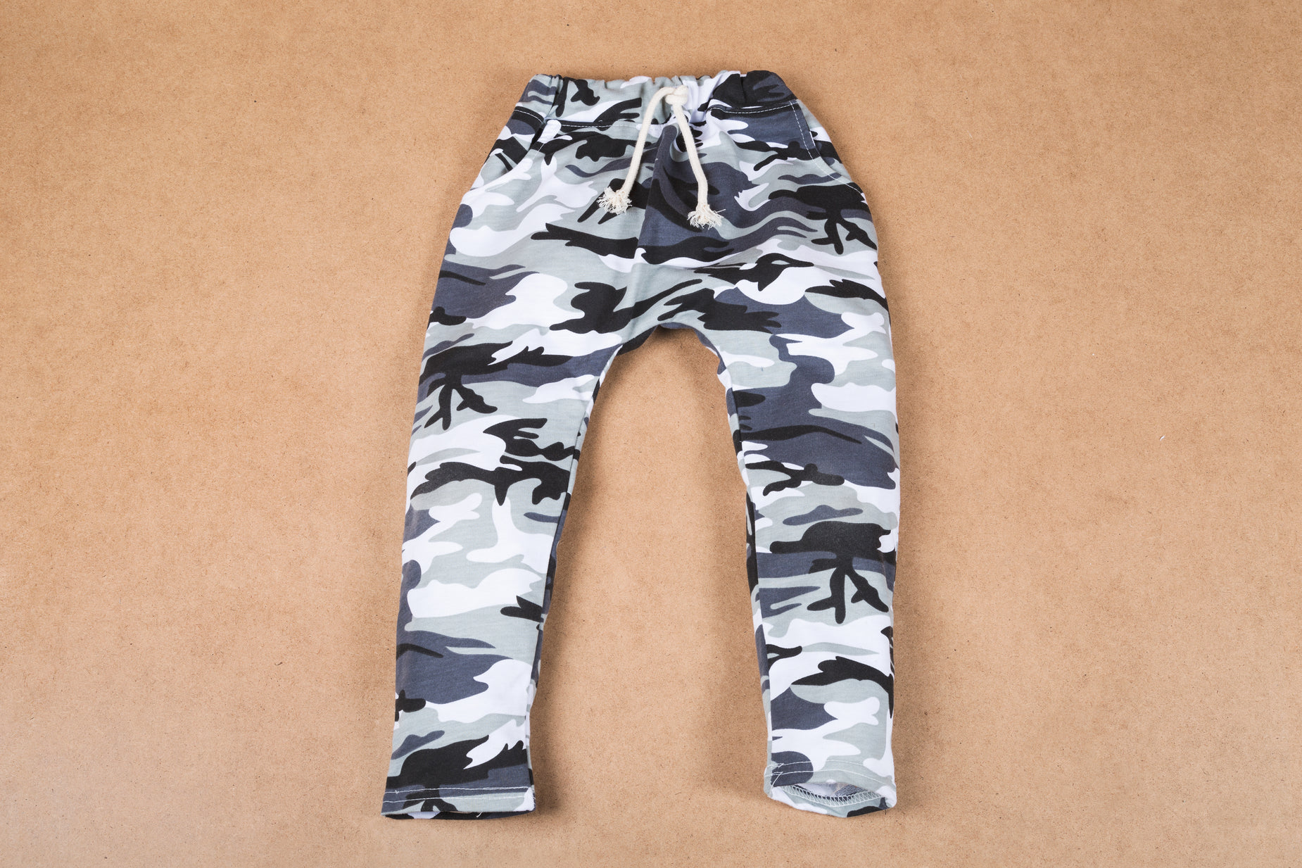 the blue camouflage pants that is sitting on top of the brown floor