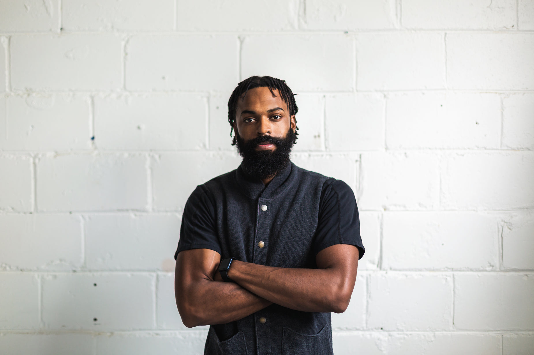 a bearded man standing with his arms crossed