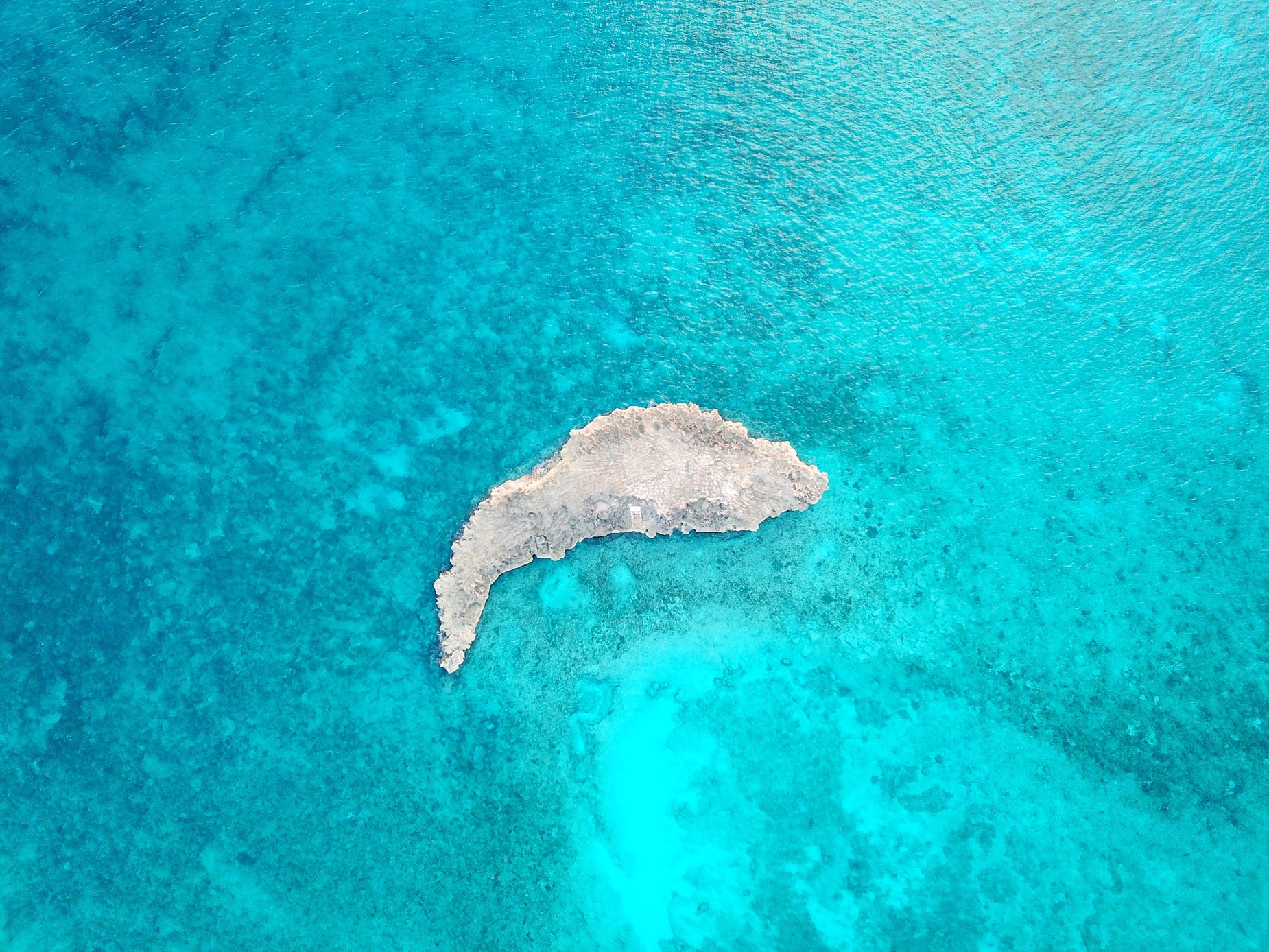 an aerial view of a very blue ocean with white island in it