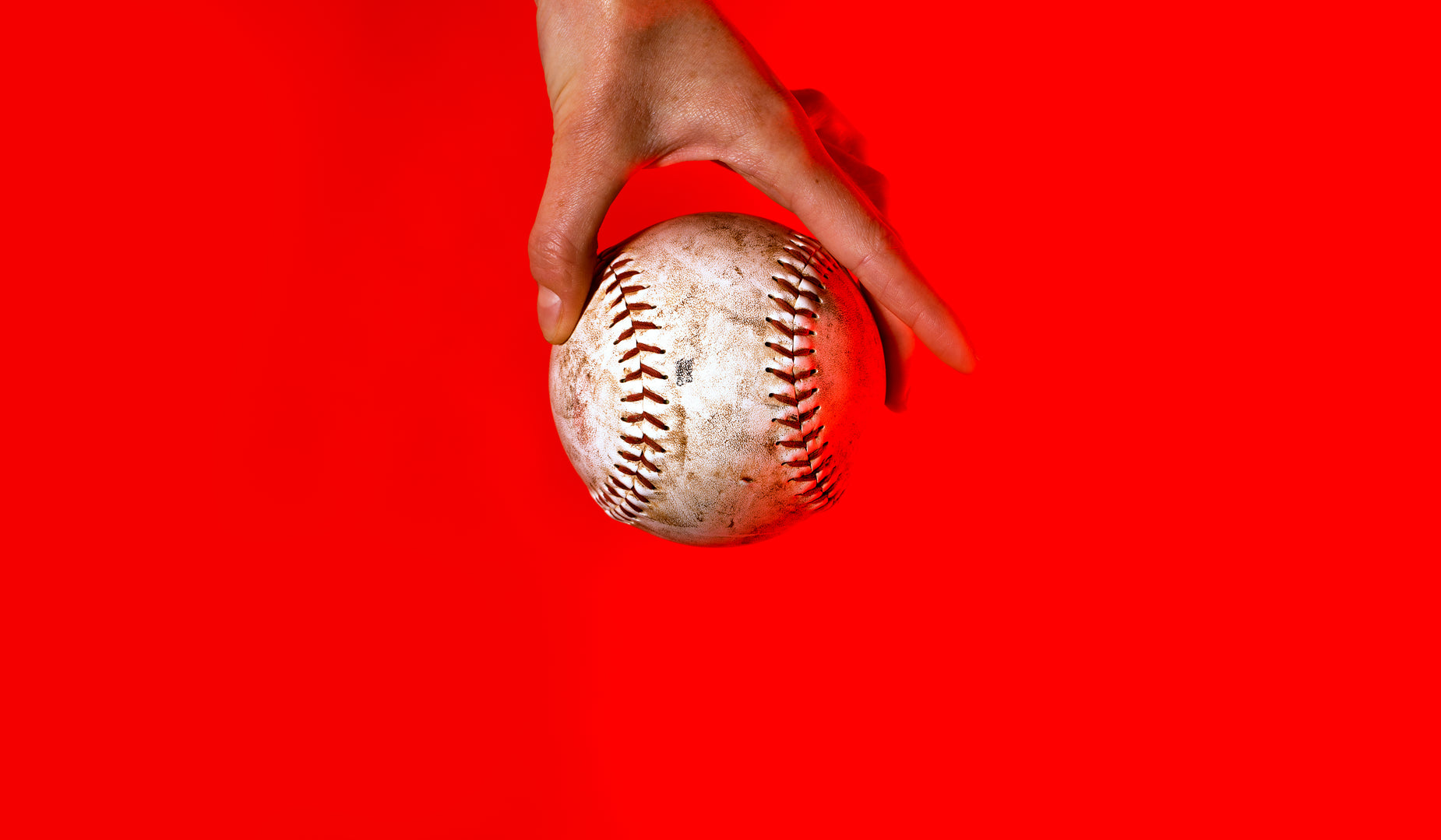 a person's hand reaching out toward a baseball
