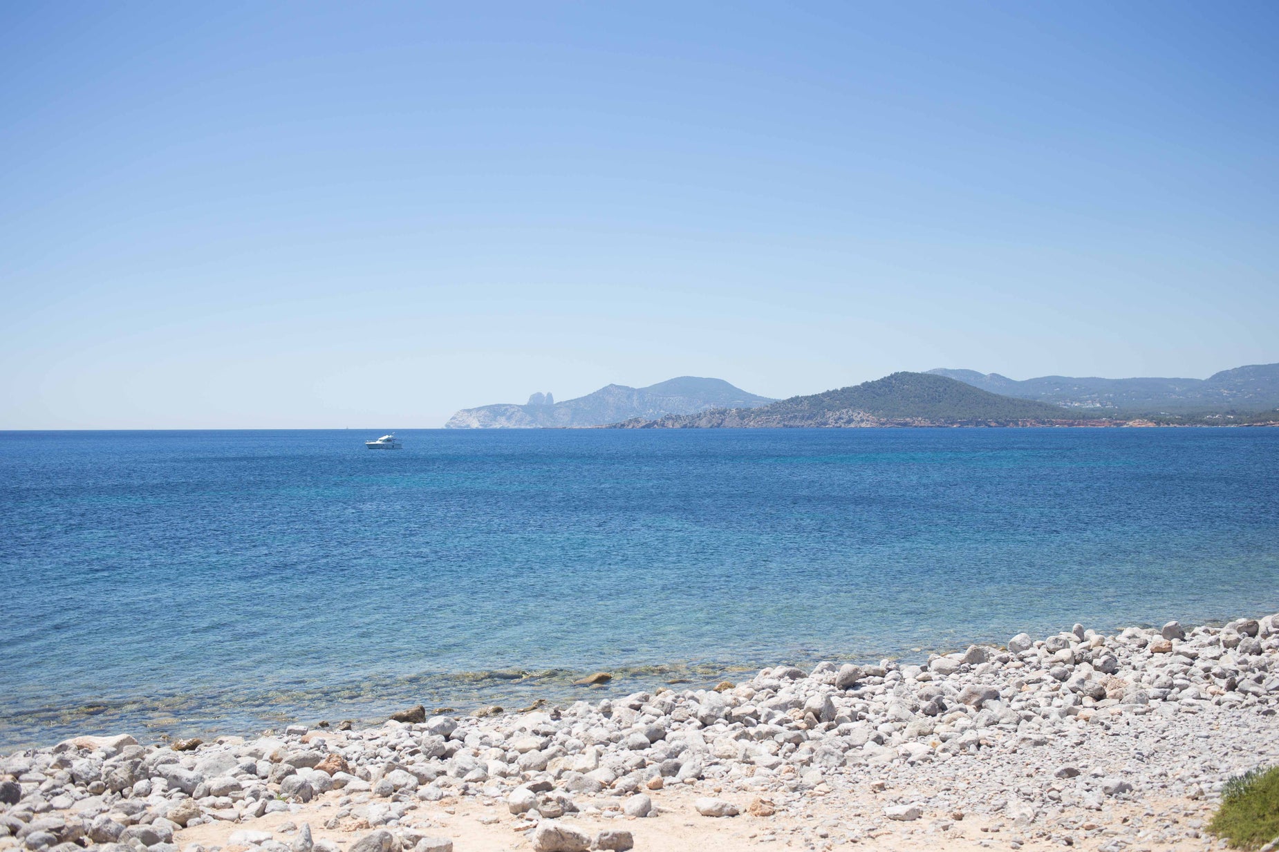 a beach with blue water and rocks on the shore