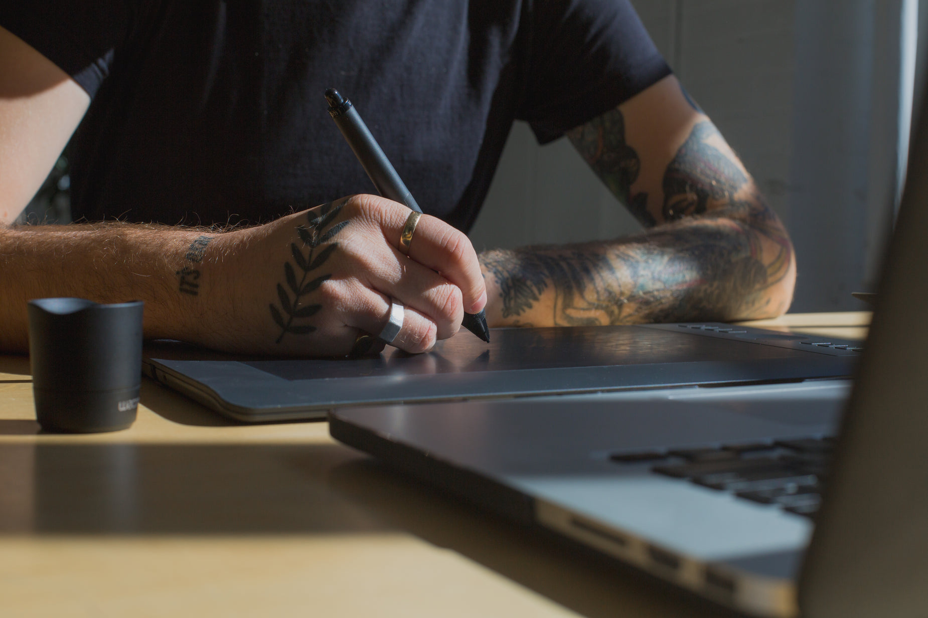 a man writes soing on his laptop while sitting at a table