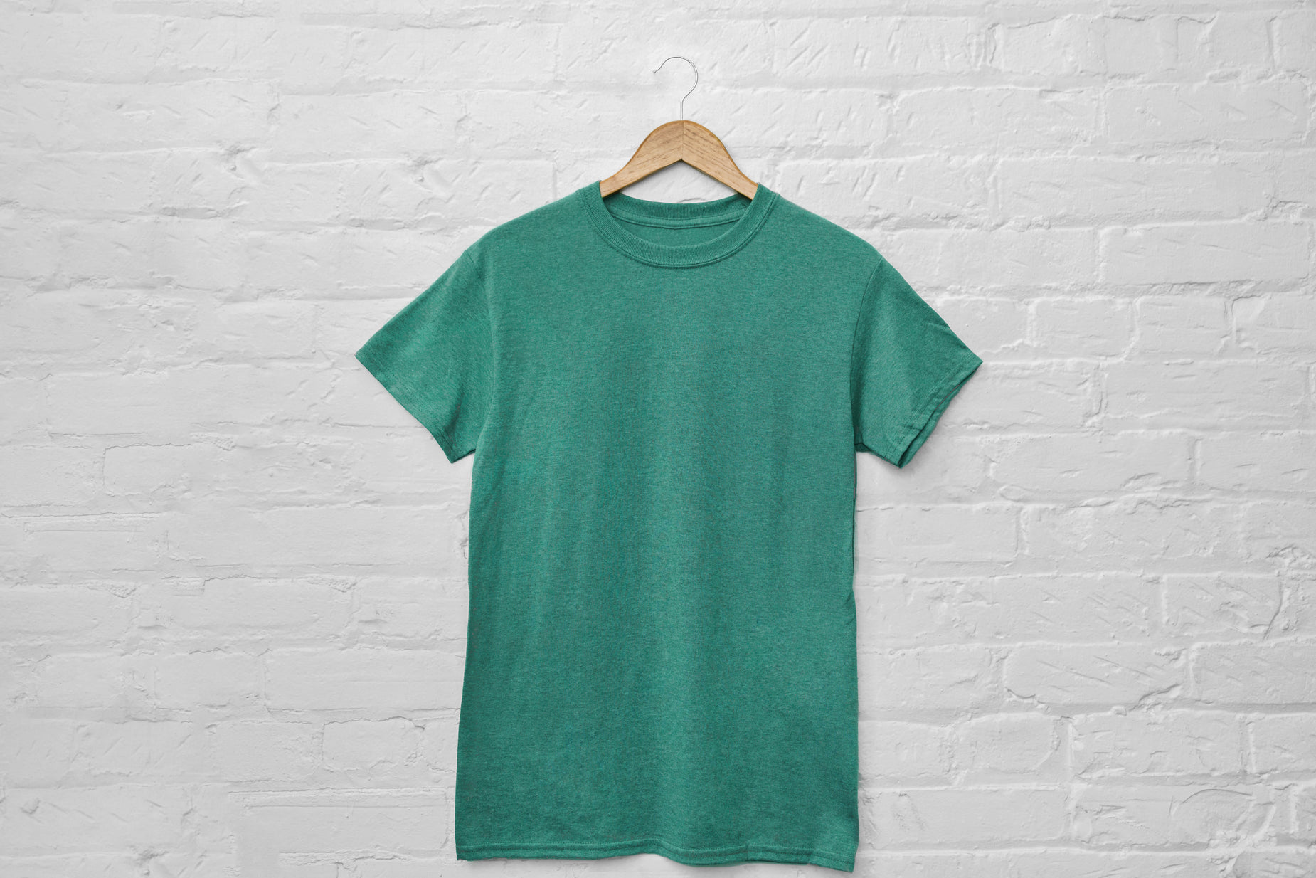 a green shirt hanging up against a brick wall