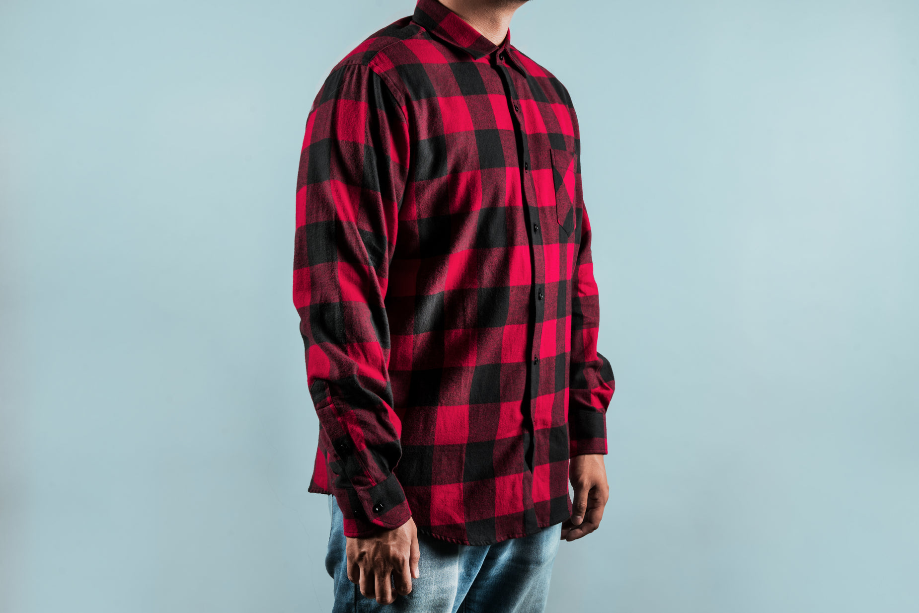 a man standing and looking off to the side wearing a red and black checkered shirt