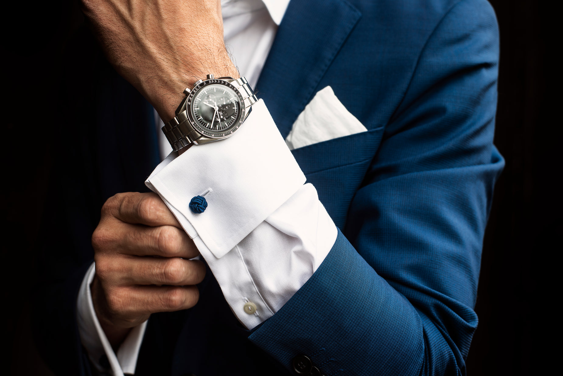 a close up of a person wearing a blue suit and holding onto his watch