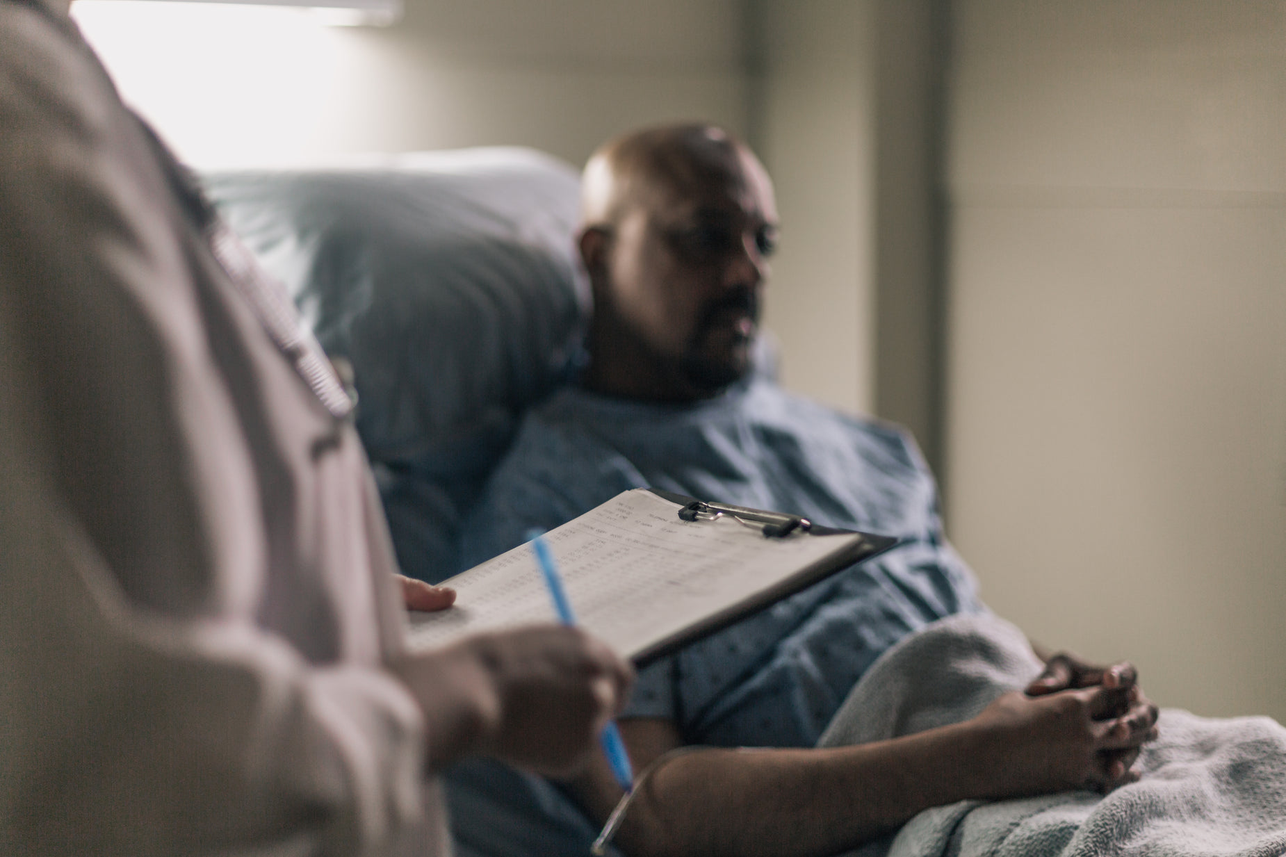 a man laying in a hospital bed with a clip board