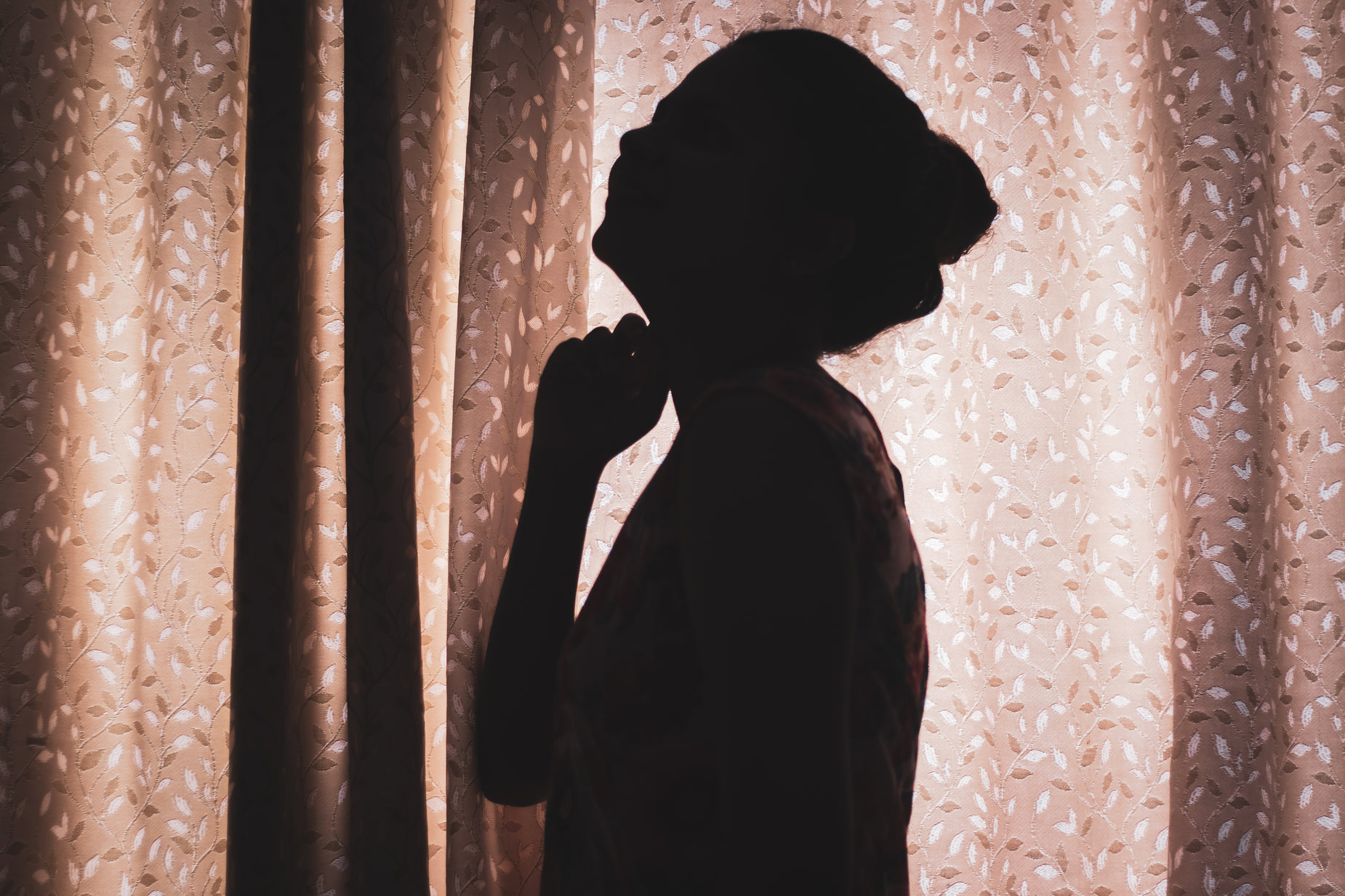 a silhouette of a person in front of a curtain