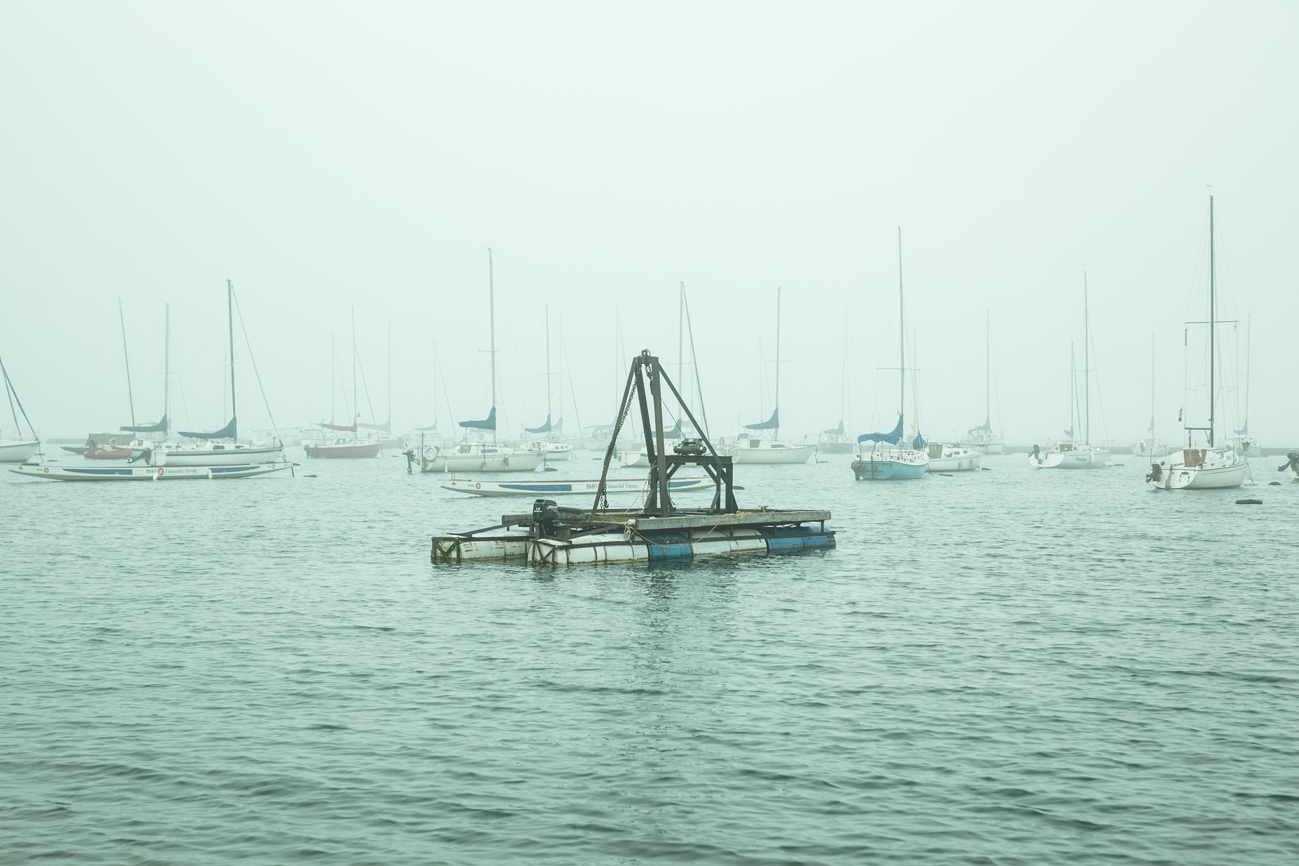 several boats anchored in the water on a foggy day