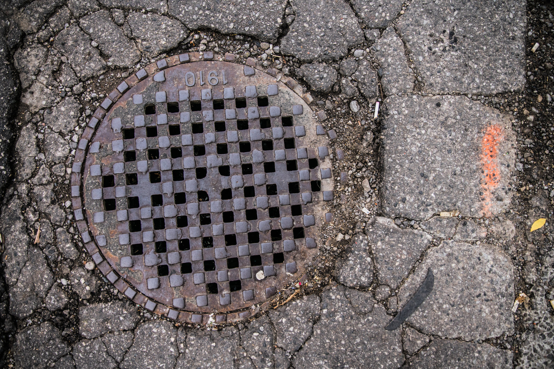 a manhole cover laying on a brick sidewalk