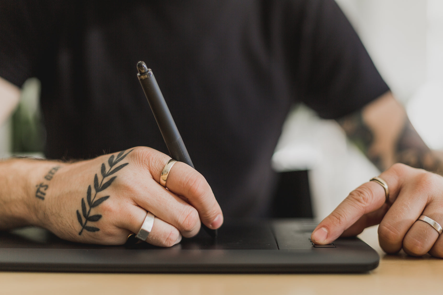 a person sitting in front of a laptop using a pen