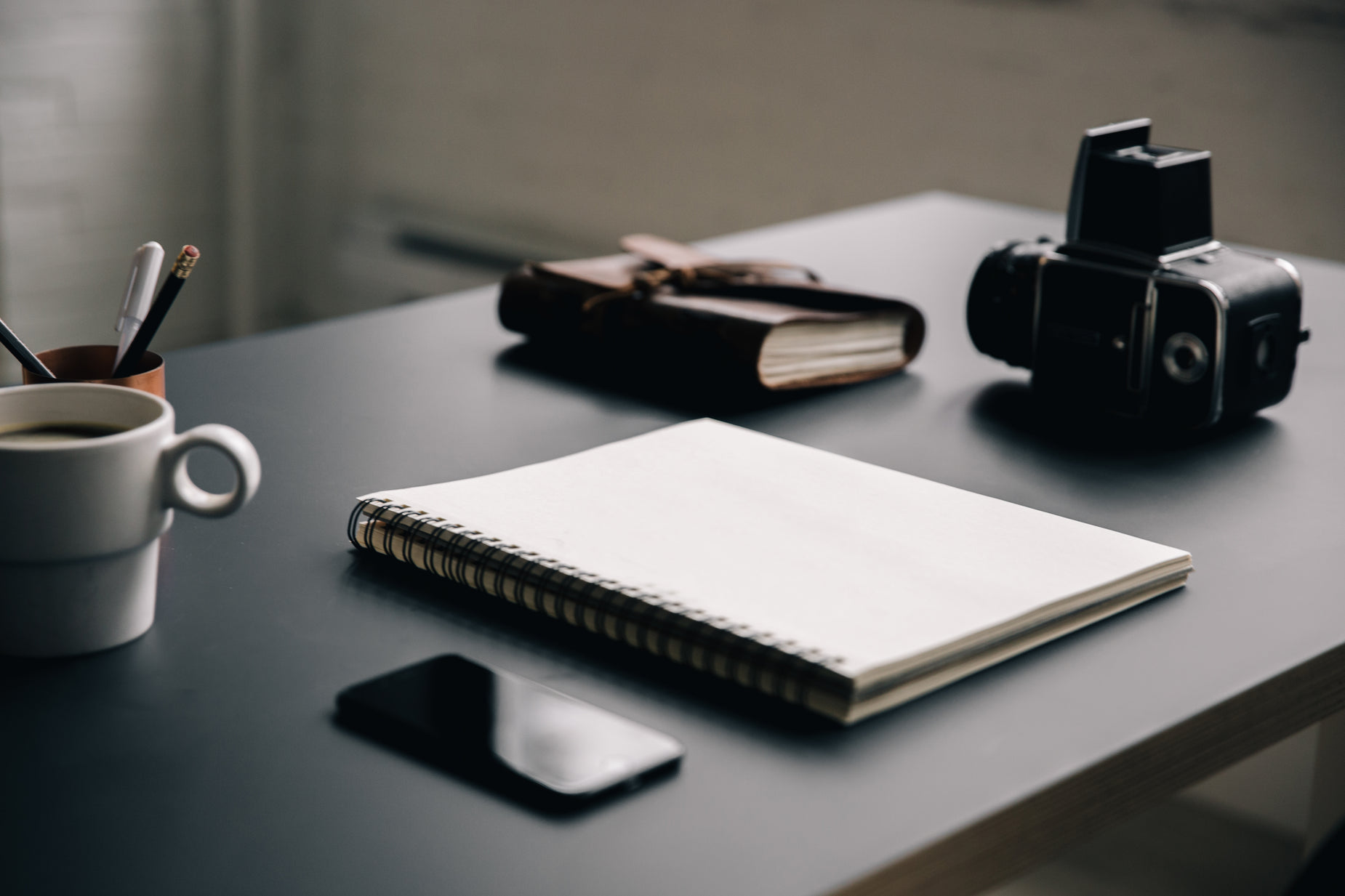 a black desk with two cameras and a notebook