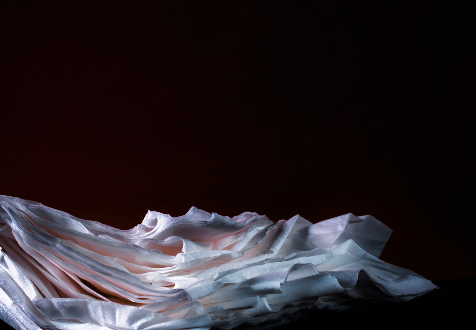 a pograph of a folded, white sheet on a black table