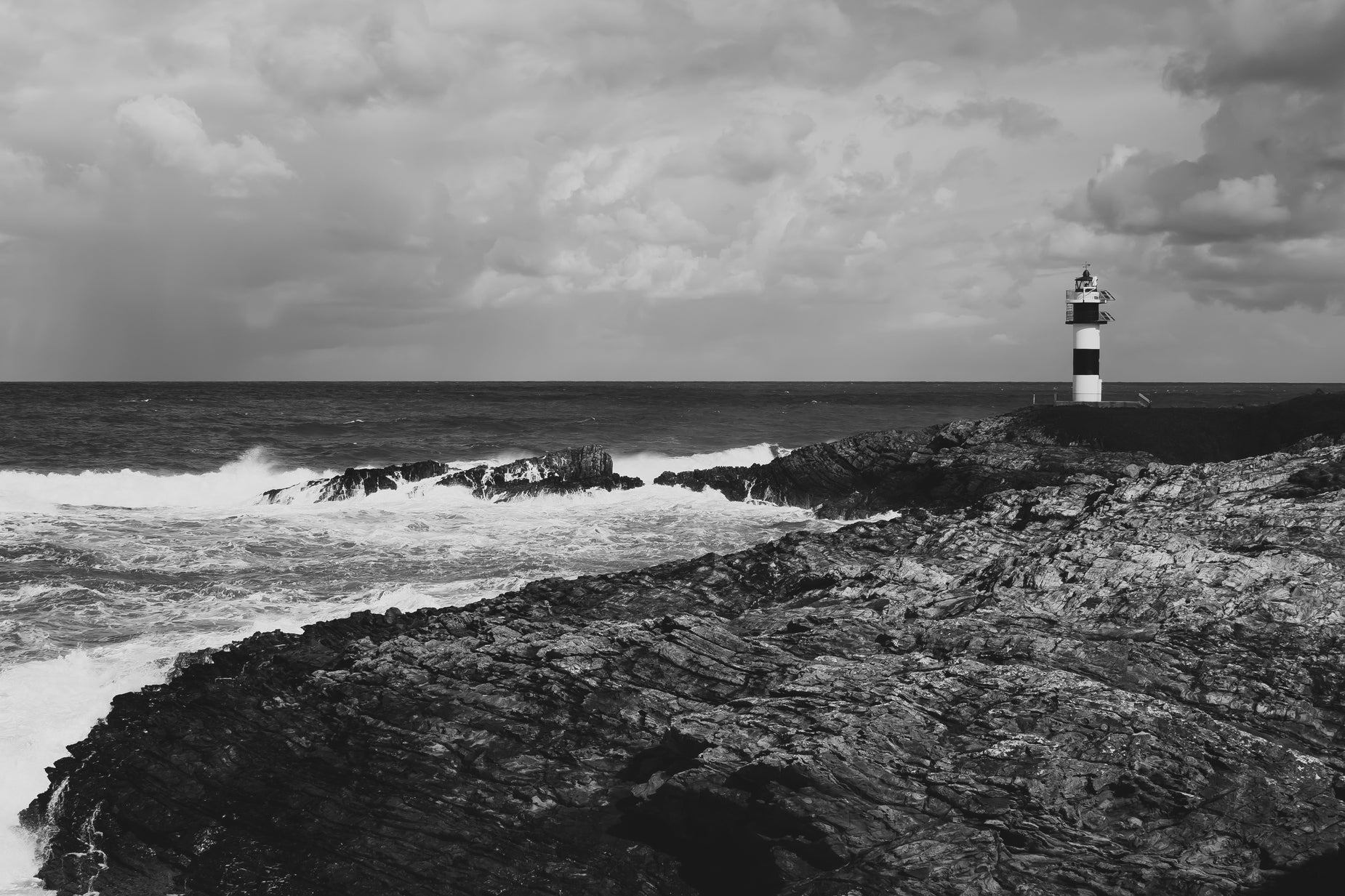 black and white pograph of an ocean lighthouse and rocky shore