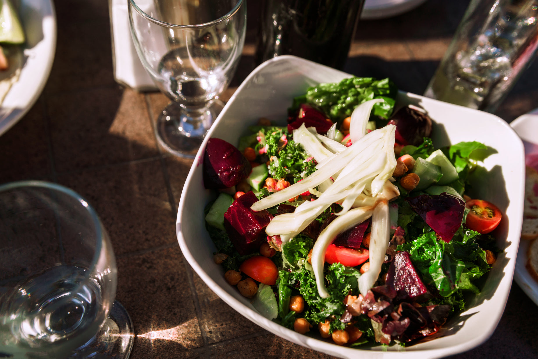 a table with two wine glasses and a salad