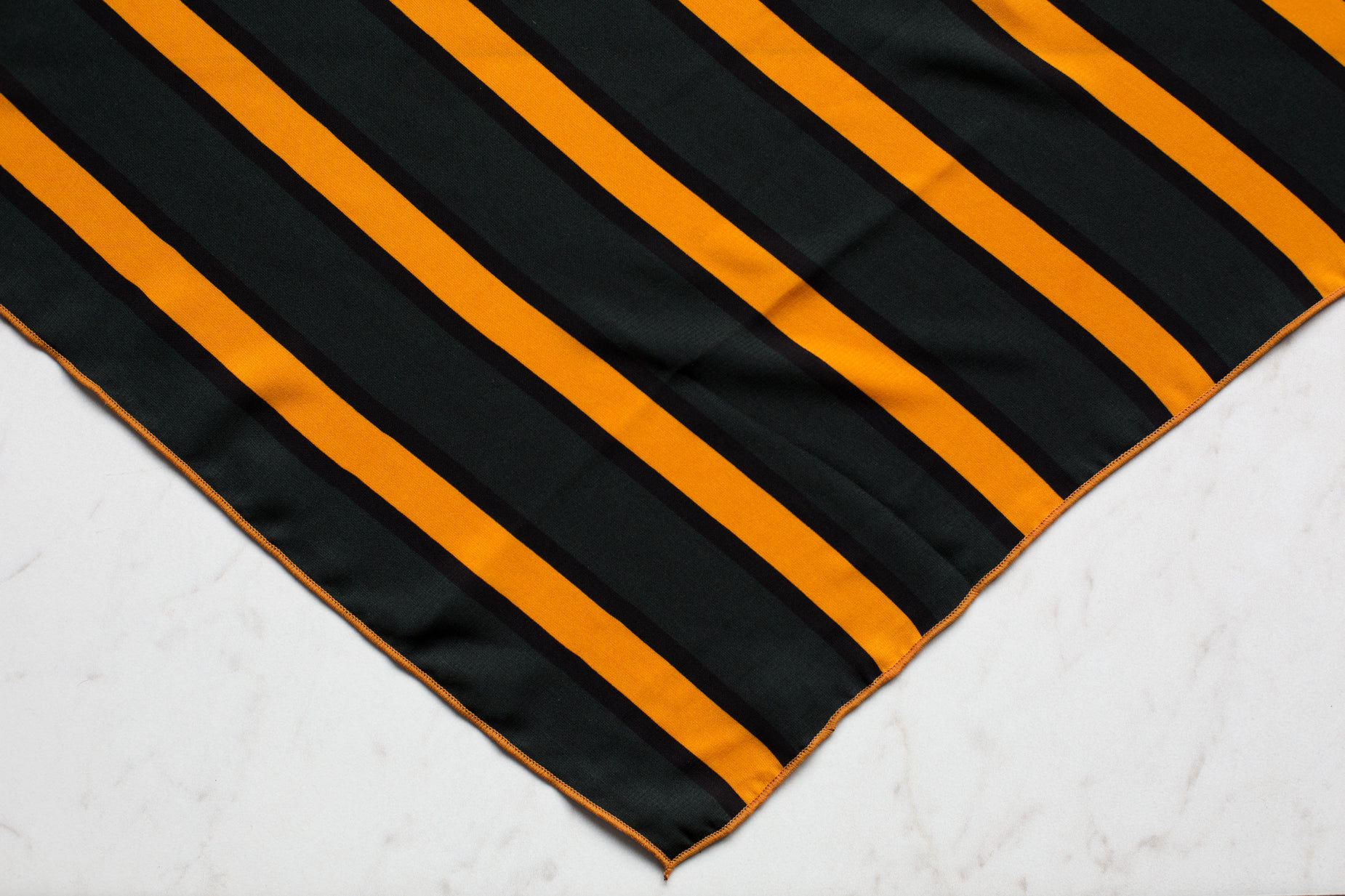a black and gold striped table runner on a white marble surface