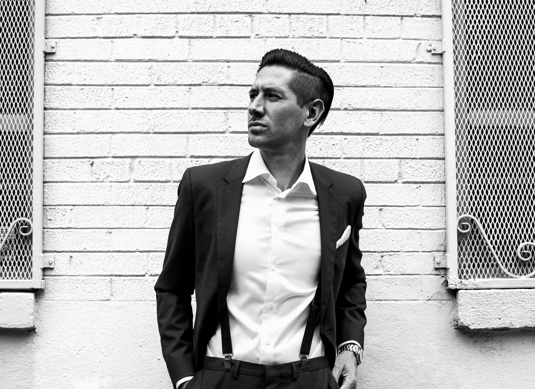 a young man is posing in front of a brick wall