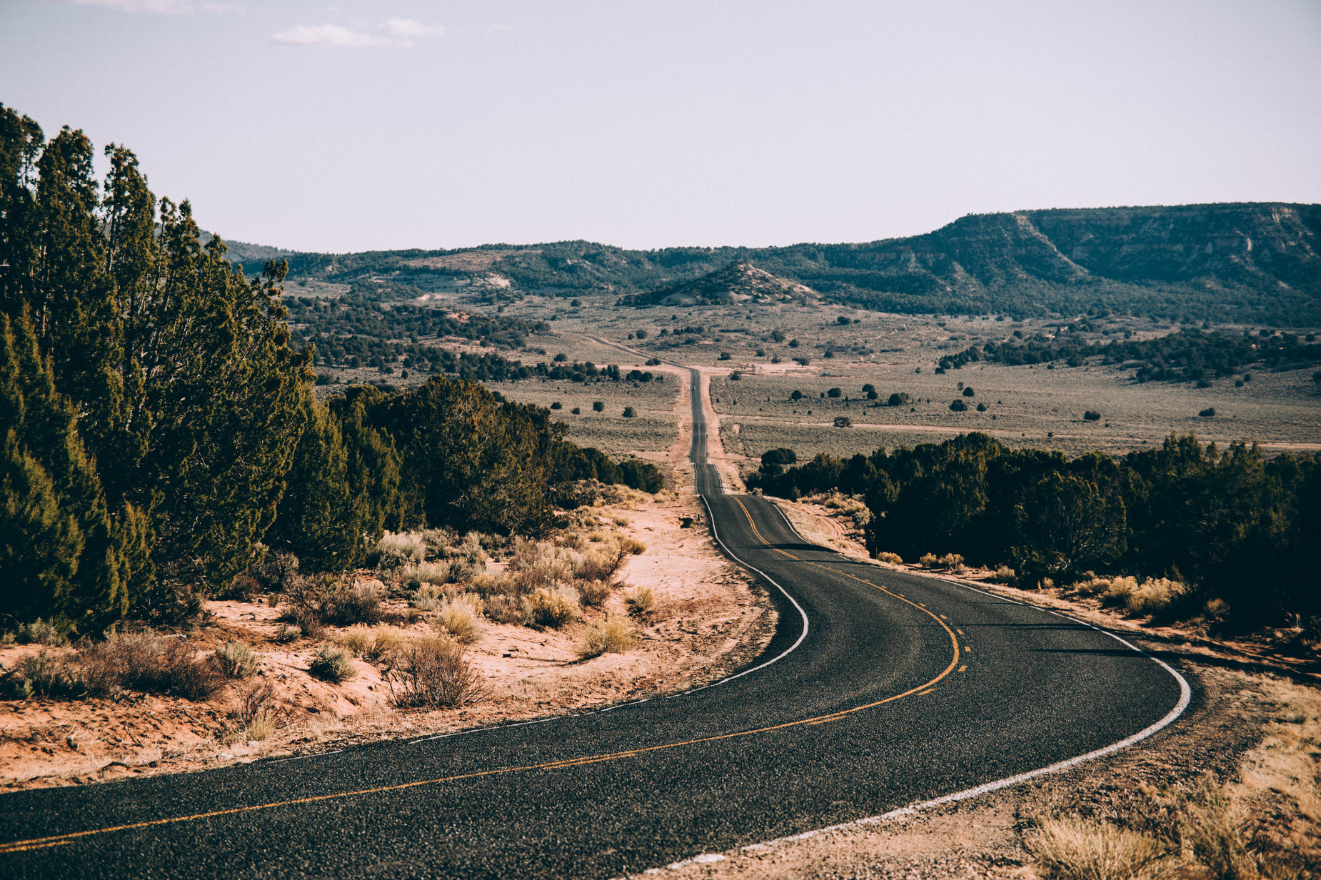 a paved road stretches to the horizon in a mountainous region