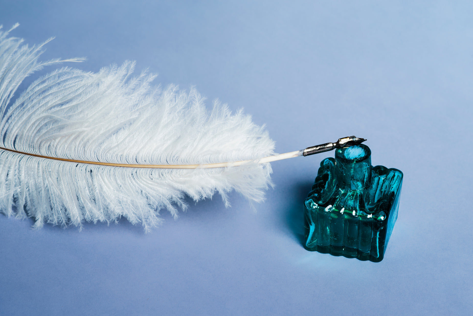 a glass feather resting next to a miniature green object