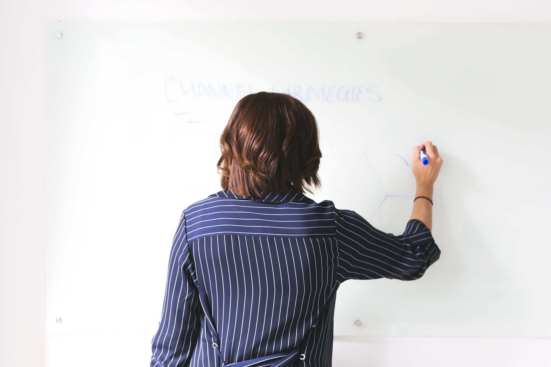 a woman writing on a white board